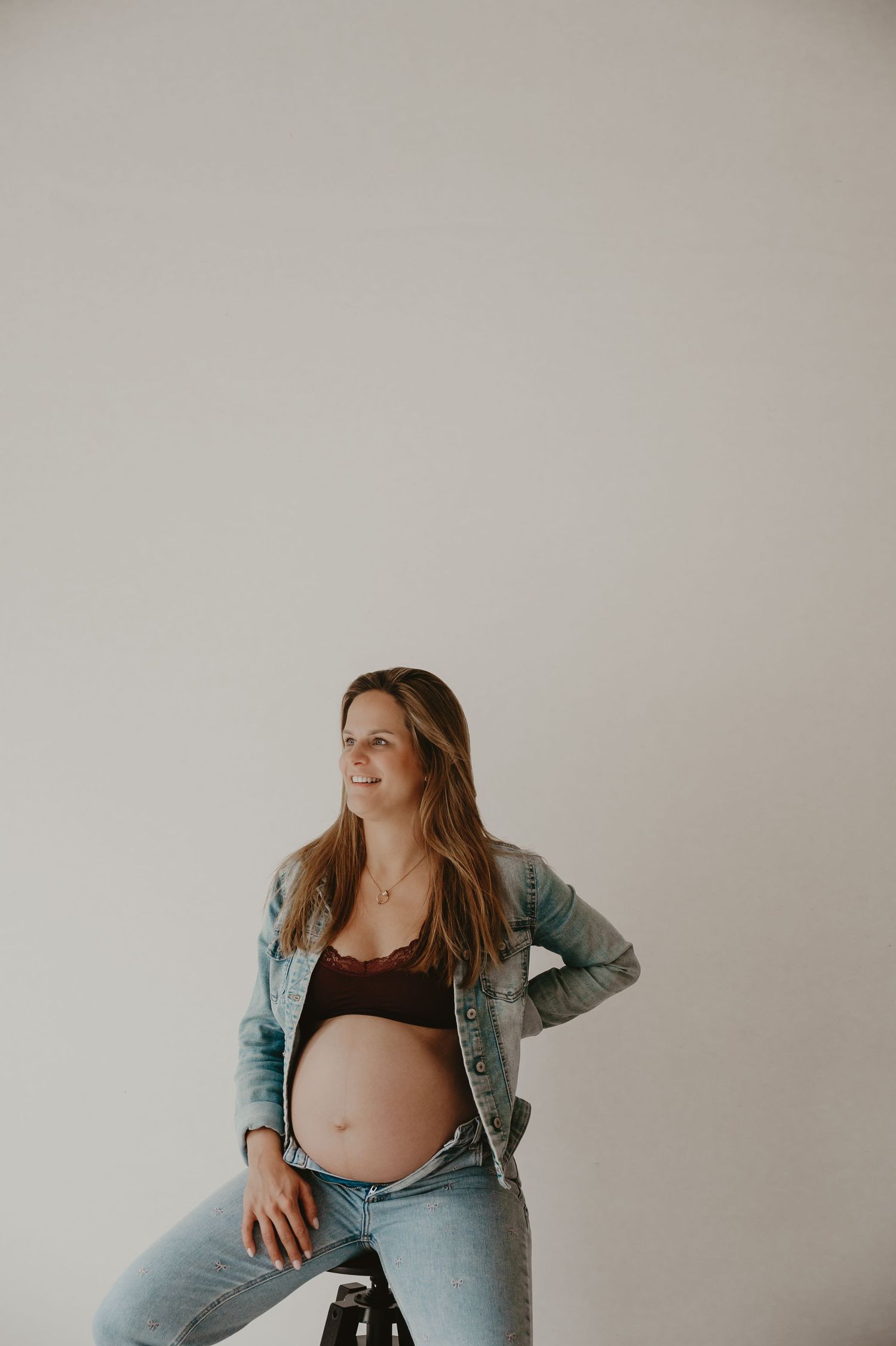 Zwangere vrouw zit op een kruk met kleurrijke lingerie, intieme zwangerschapsfotografie fotograaf Roeselare
