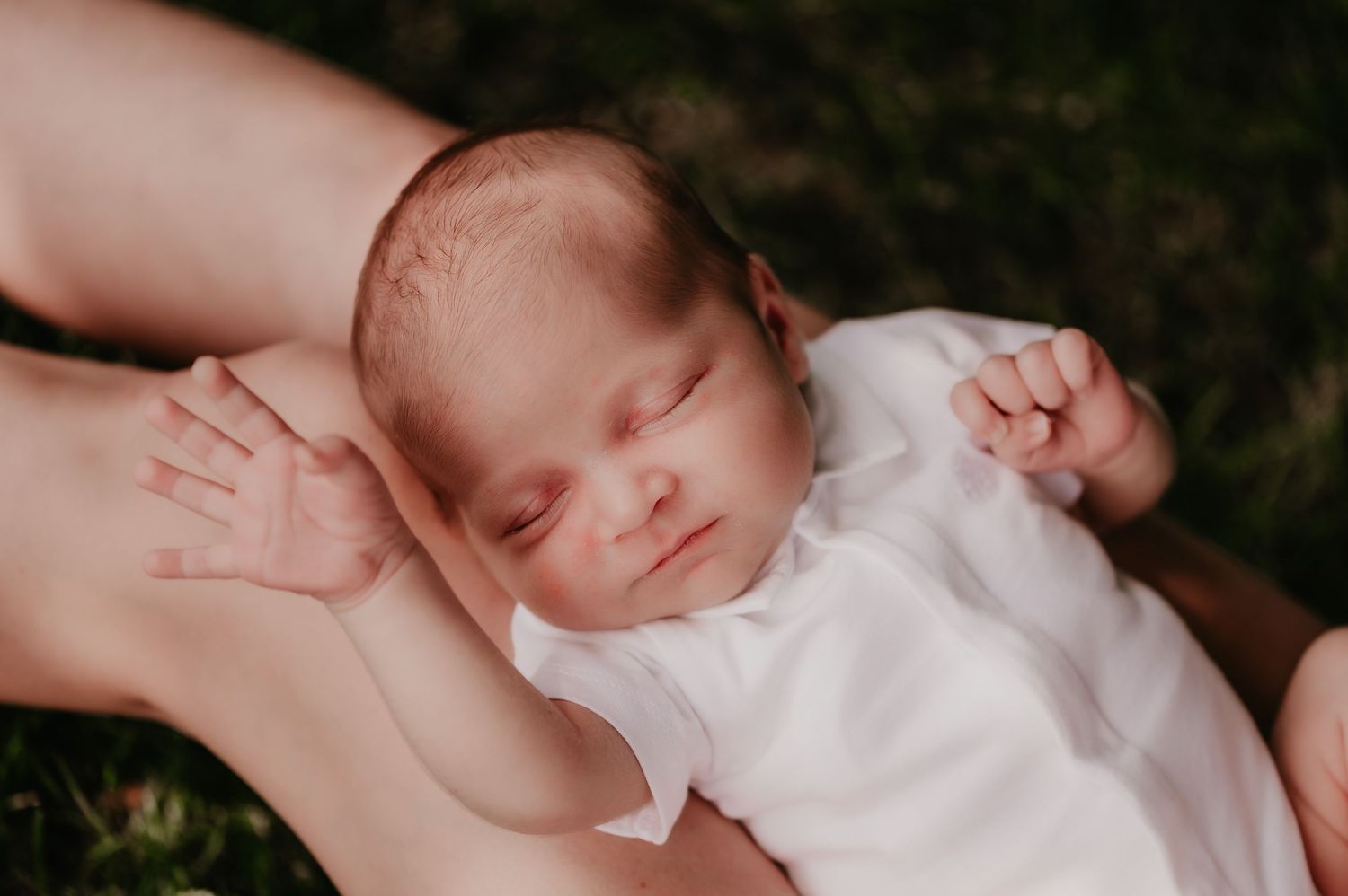 Slapende newborn baby met armpjes gespreid in witte romper, geboortefotografie West-Vlaanderen