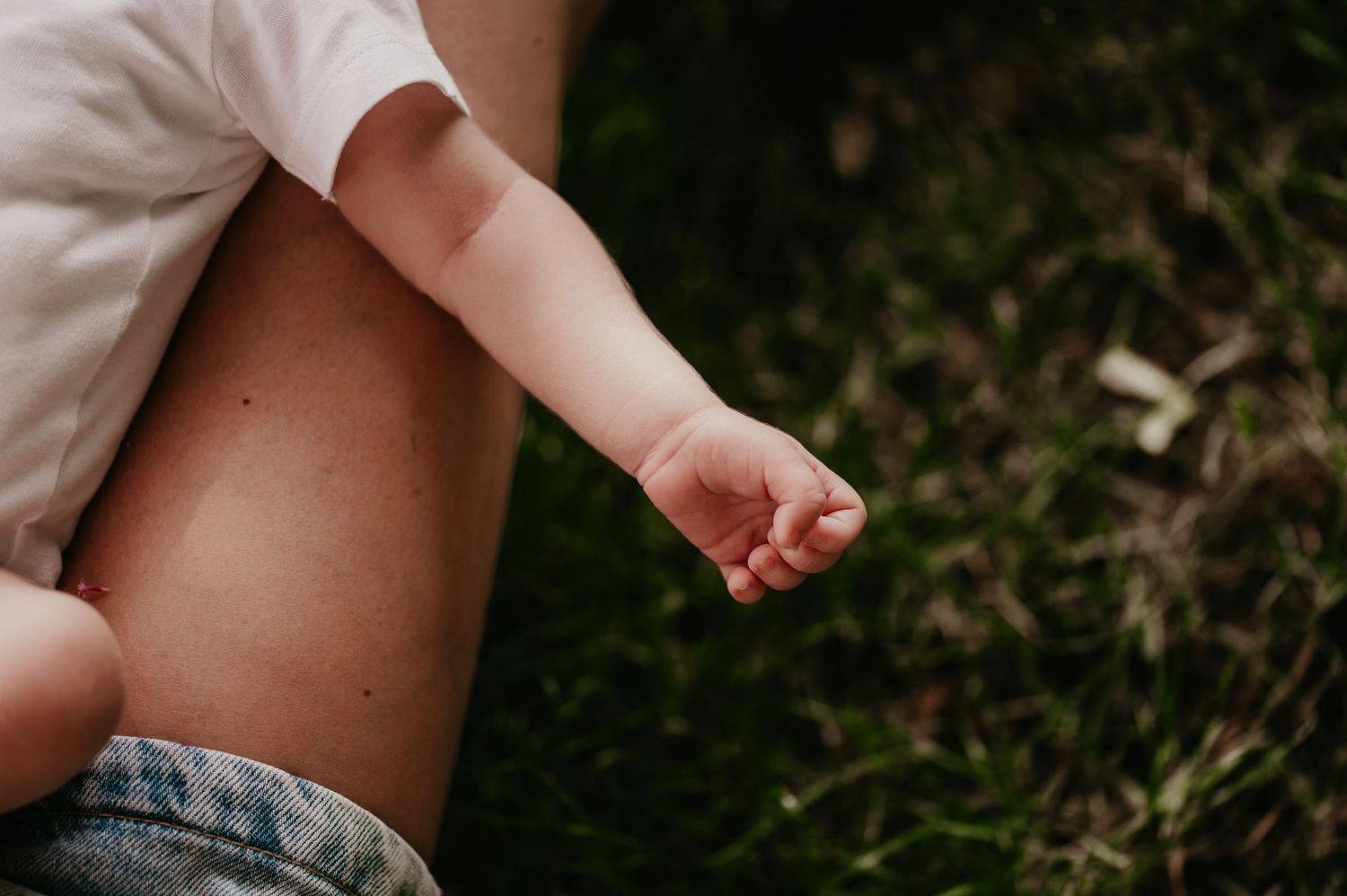 Close-up van uitgestrekte babyvuistje buiten in het gras, geboortereportage fotograaf Roeselare