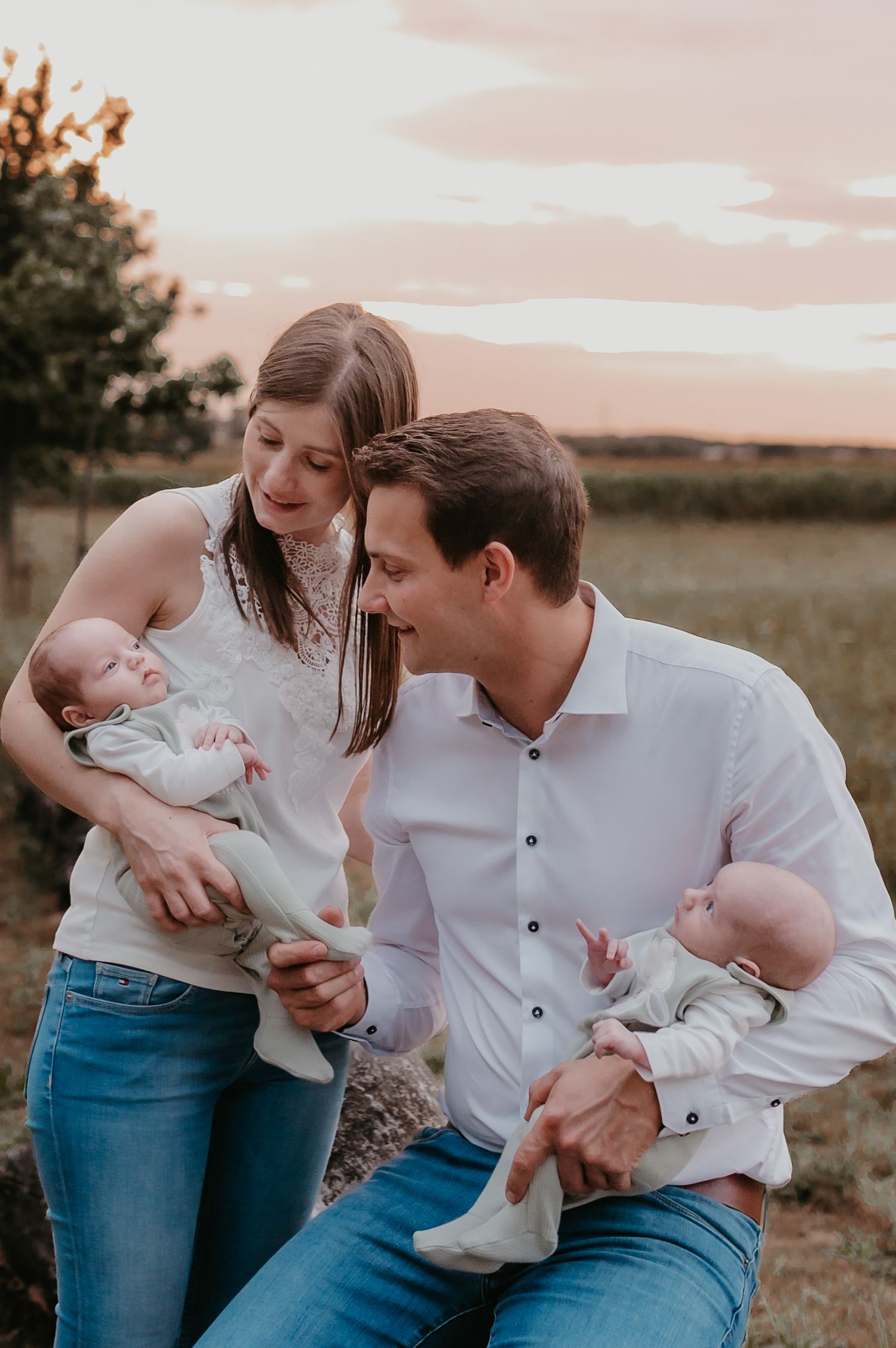 Ouders houden elk een tweeling vast buiten bij zonsondergang, tweeling geboortereportage Roeselare