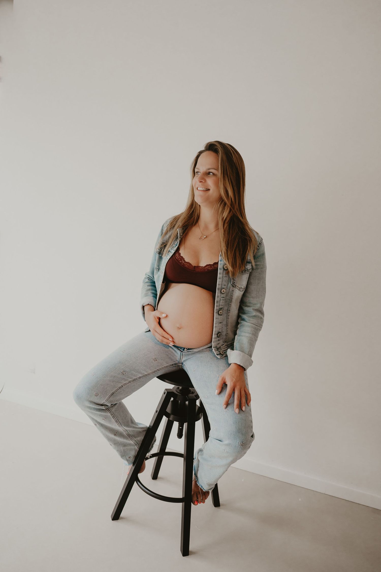 Zwangere vrouw staat naast een kruk in studio, fine art zwangerschapsfotografie zwangerschapsfotograaf Roeselare