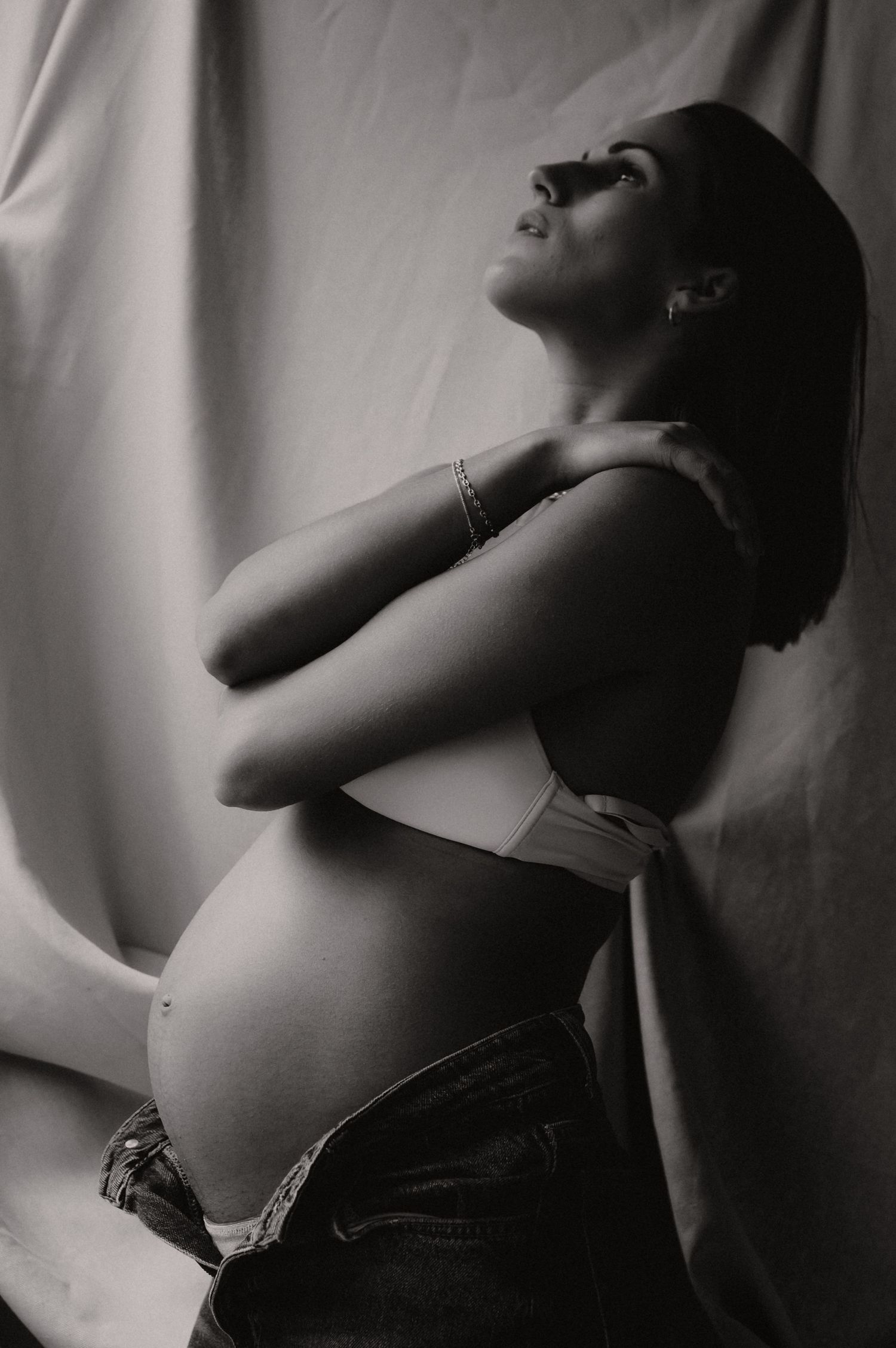 Zwangere vrouw poseert van opzij met dramatisch zwart-wit licht, fine art zwangerschapsfotografie Roeselare