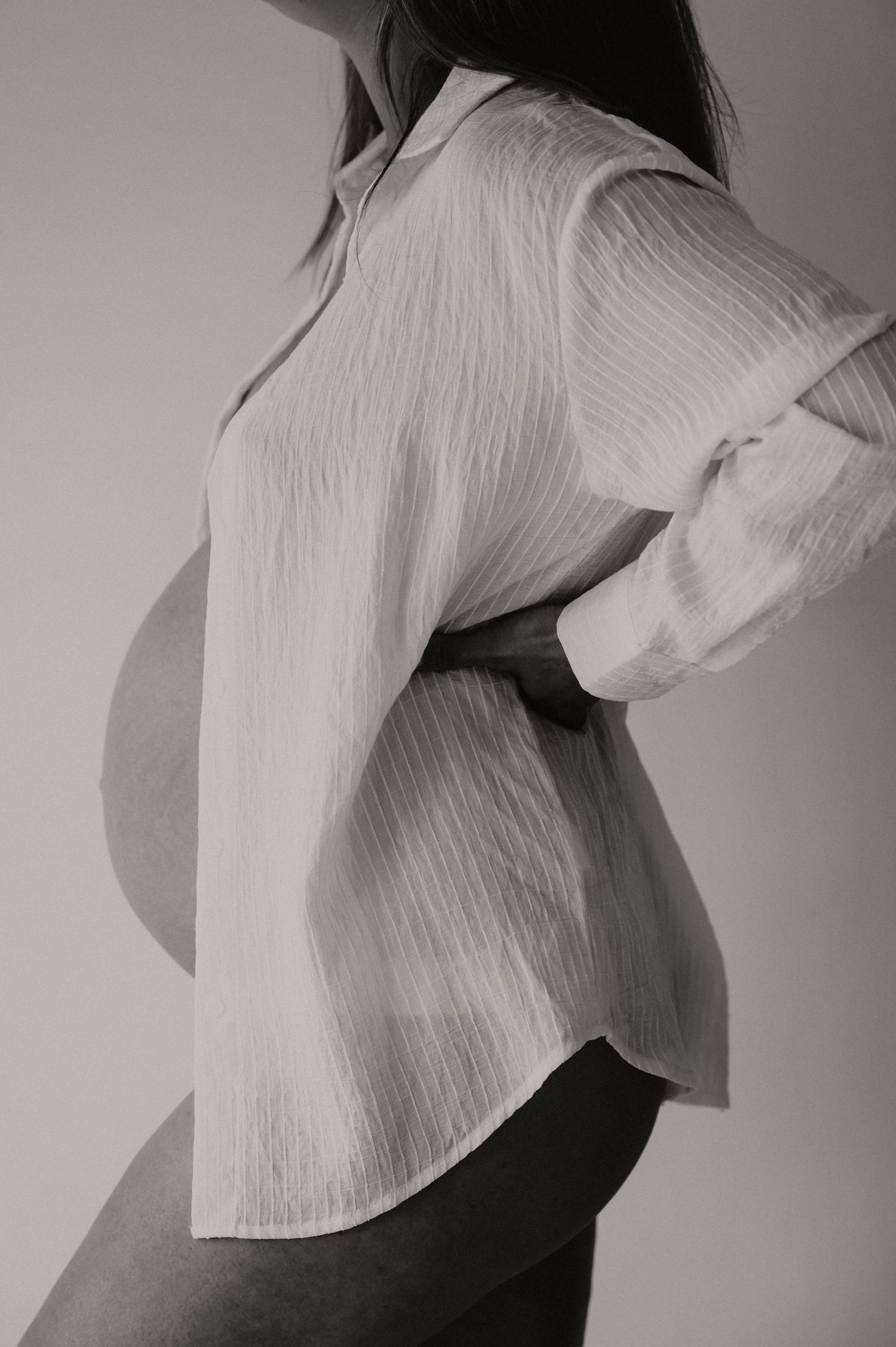 Zwanger silhouet van achter in elegante linnen blouse, artistieke zwangerschapsfotografie Roeselare