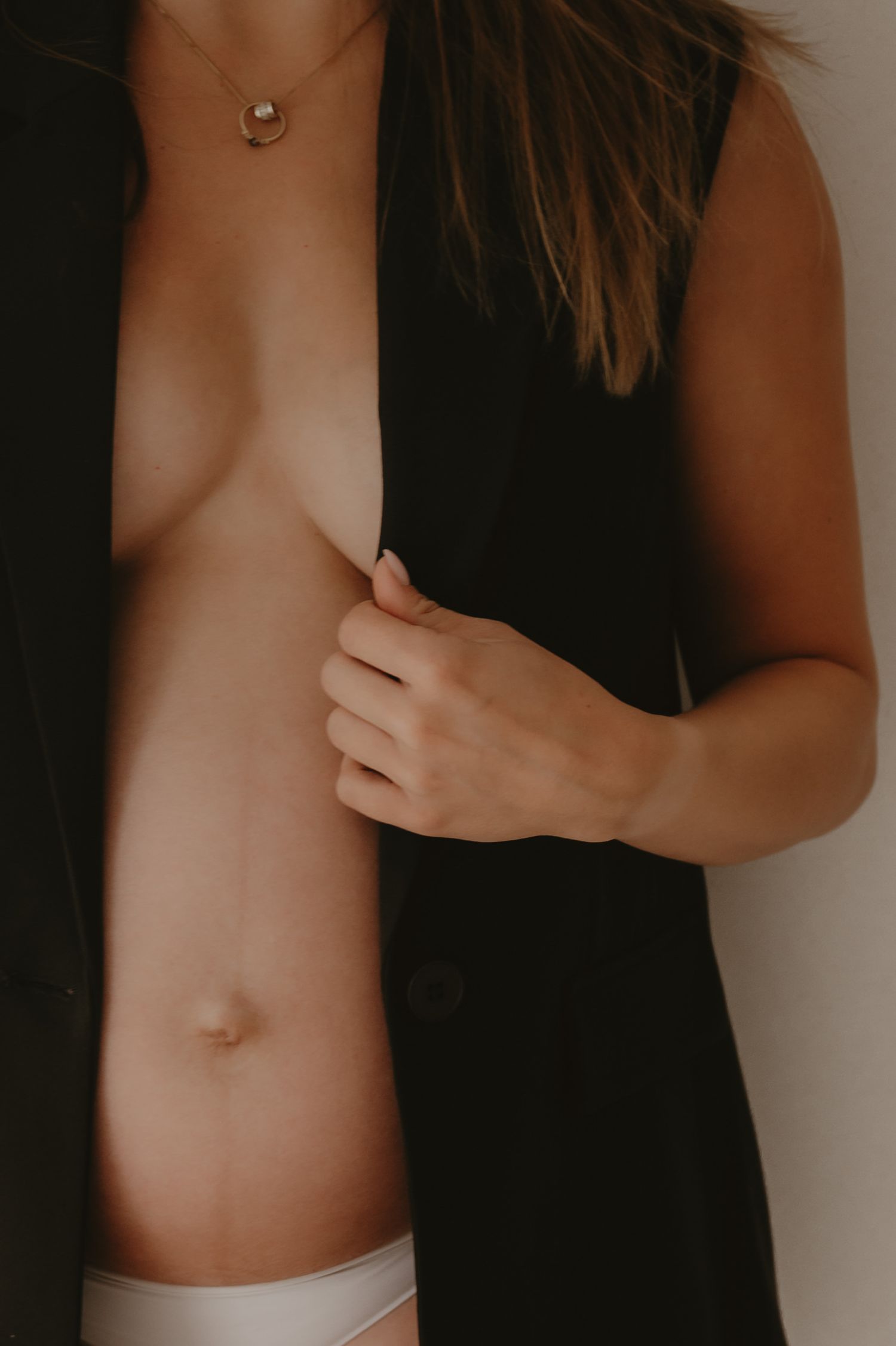 Zwangere vrouw streelt haar ronde buik van opzij, tedere close-up zwangerschapsfoto Roeselare