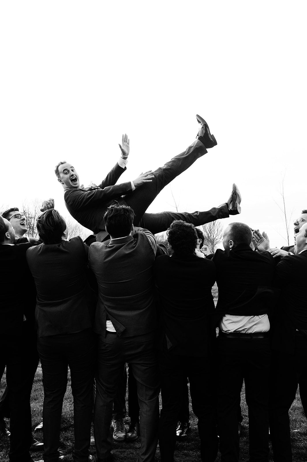 Vrienden gooien de bruidegom de lucht in — destination wedding photographer Belgium