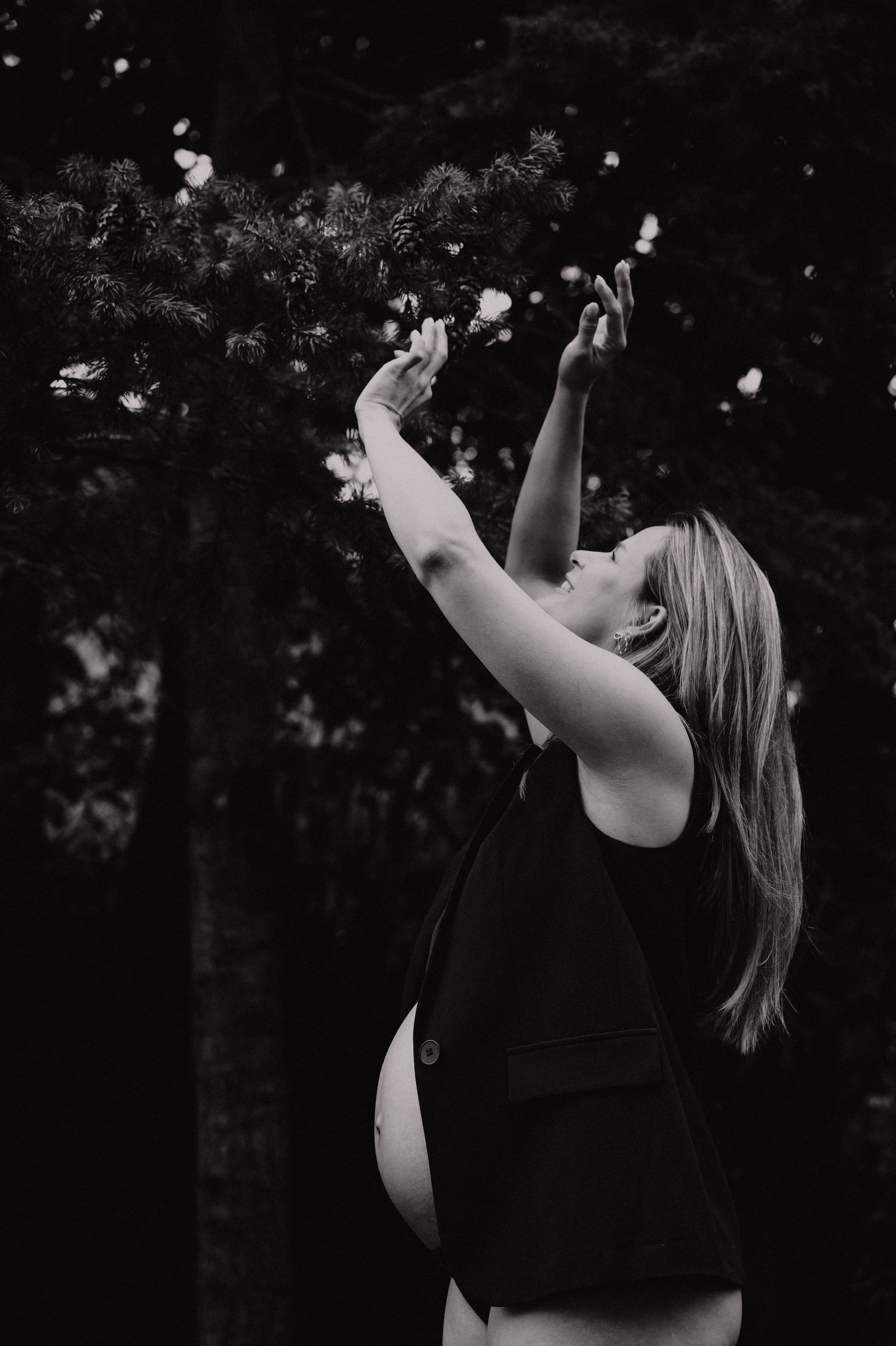Zwangere vrouw danst vrij buiten in zwart-wit, speelse zwangerschapsfotografie West-Vlaanderen