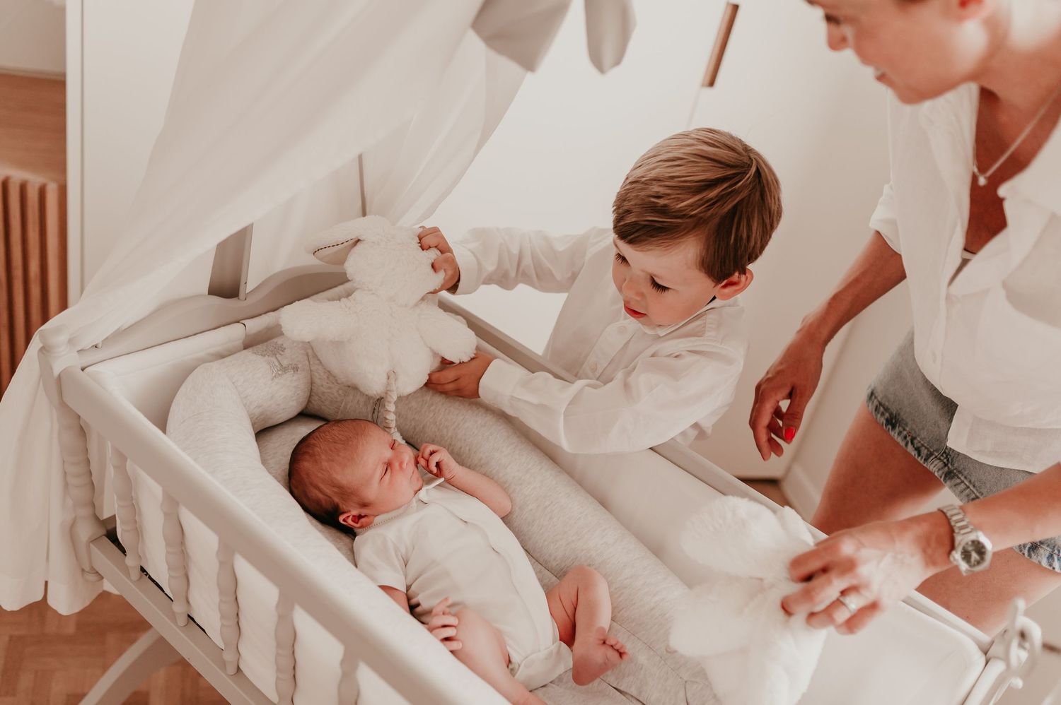 Grote broer toont een knuffelkonijn aan pasgeboren baby Omer in zijn wiegje, newborn Roeselare