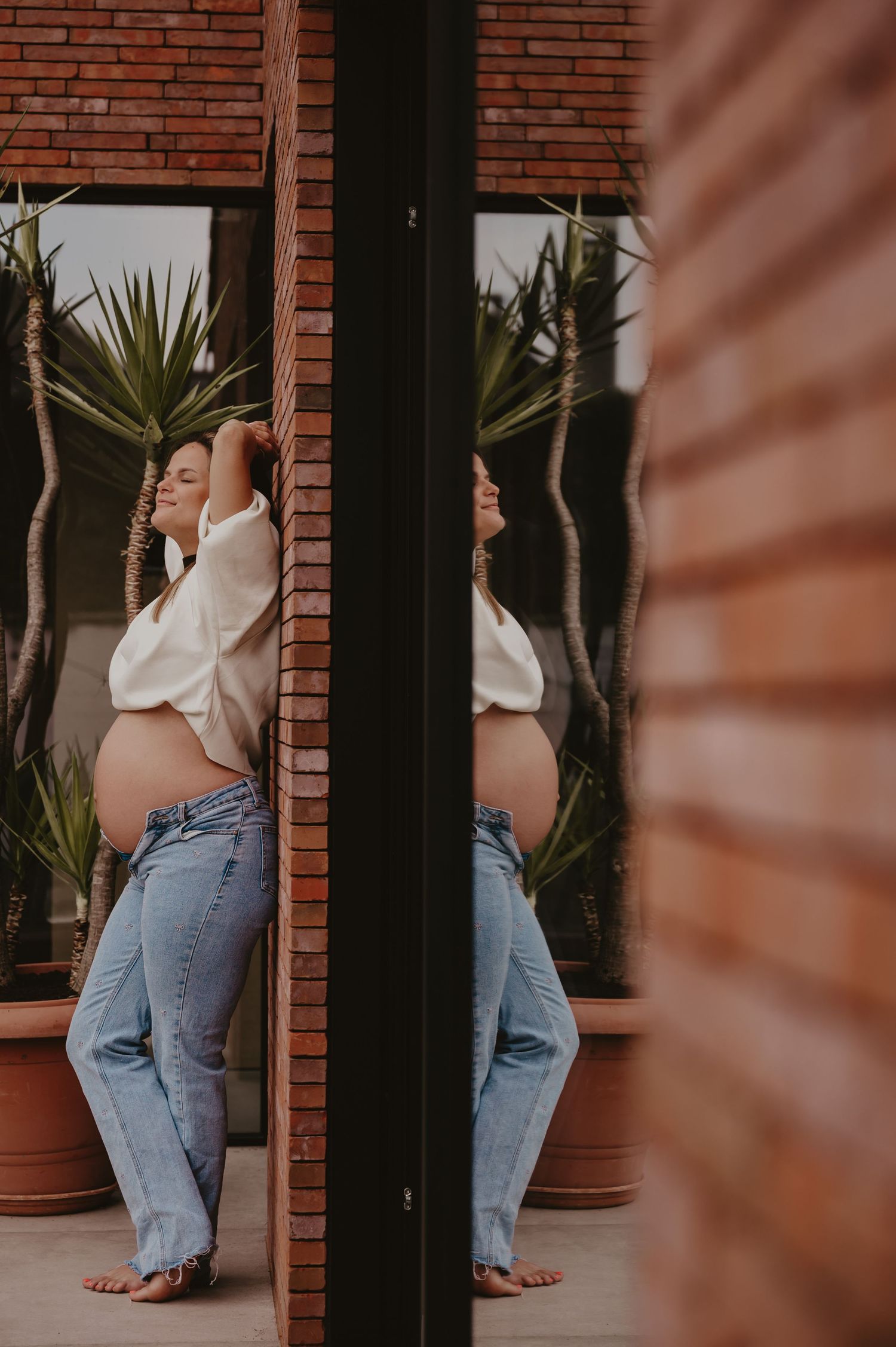 Zwangere vrouw staat voor een kleurrijke deur in bakstenen muur, urban zwangerschapsfotografie West-Vlaanderen