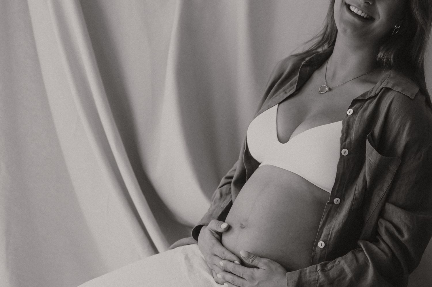 Zwangere vrouw in grijze satijnen stof geposeerd in studio, moodvolle zwangerschapsfotografie Roeselare