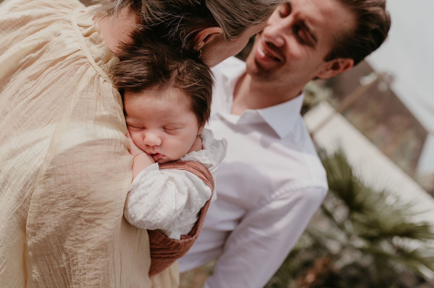 Mama en papa houden slapende baby Alma buiten in de armen, geboortefotografie West-Vlaanderen
