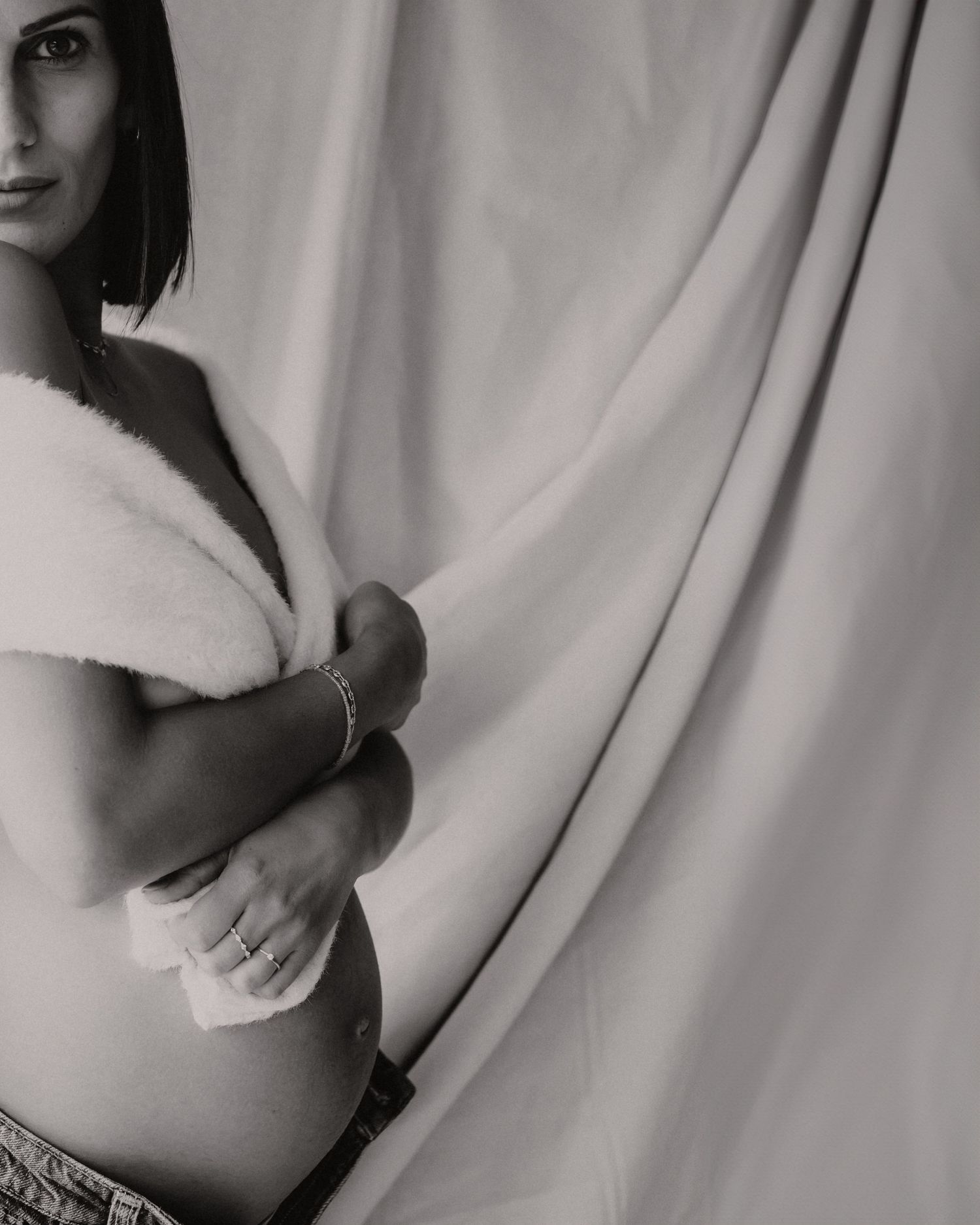 Zwangere vrouw staat elegant naast witte stof in zwart-wit, fine art zwangerschapsfotografie West-Vlaanderen