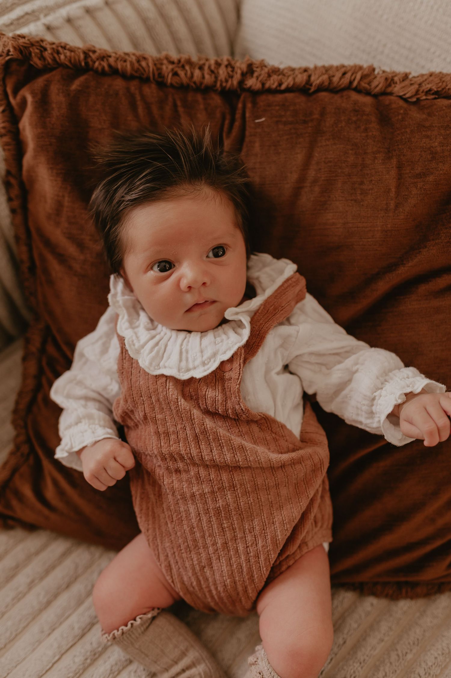 Baby Alma in roestbruine romper liggend in een rieten mandje, geboortereportage fotograaf Roeselare