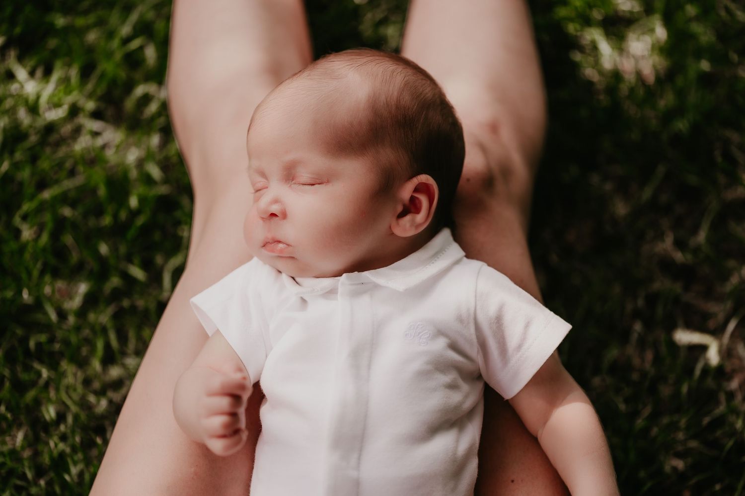 Slapende pasgeboren baby Omer op mama's schoot in het gras, outdoor newborn shoot Roeselare