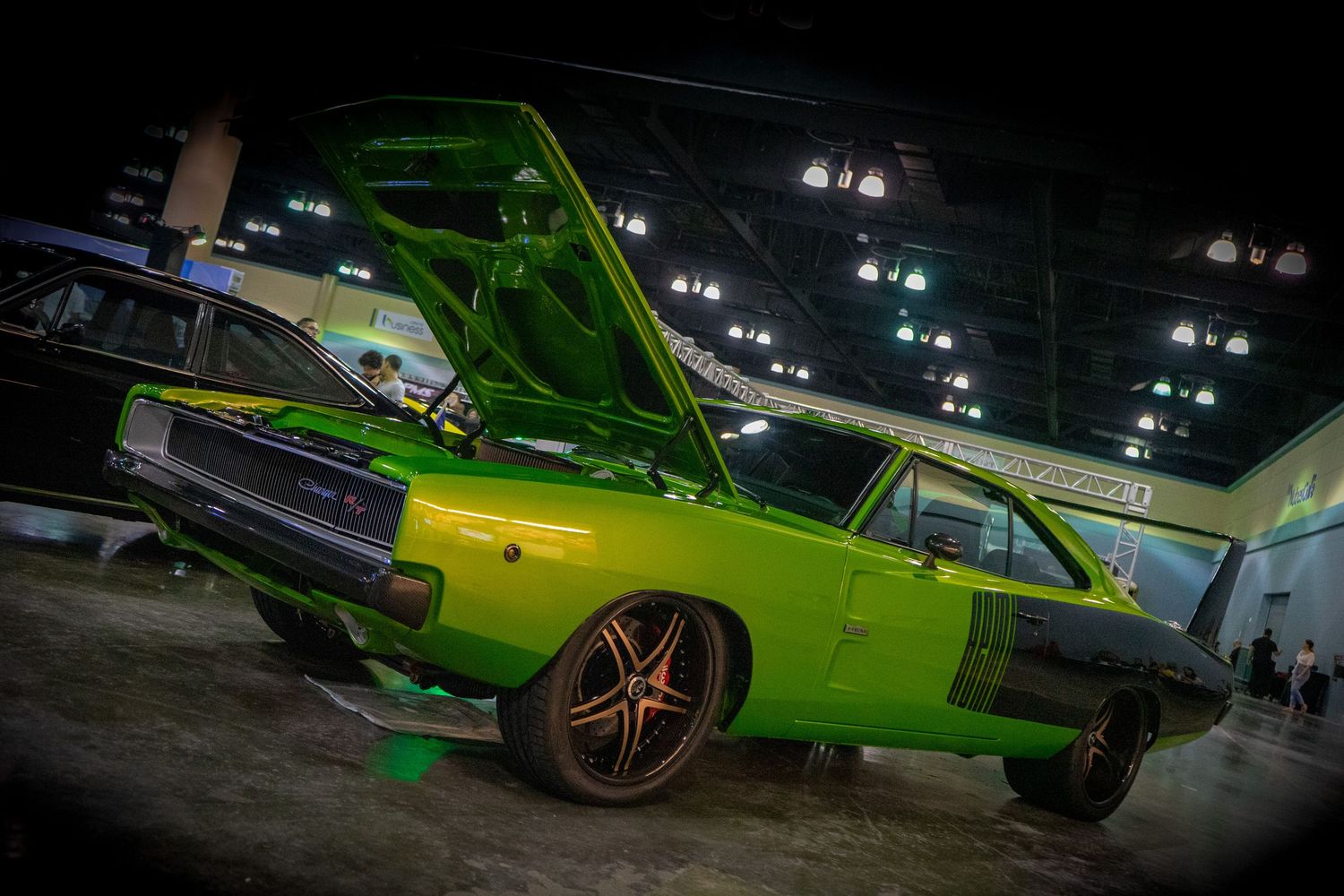 Classic bright green muscle car on display at indoor auto show with dramatic lighting.