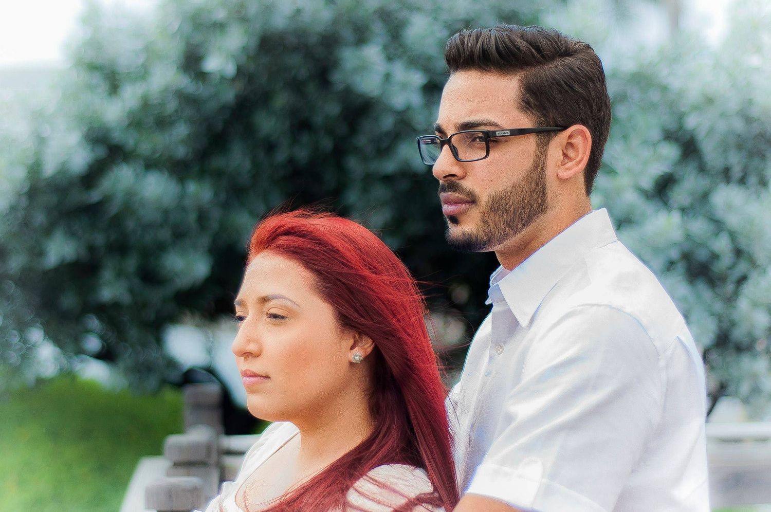 A profile view of a couple standing together against a soft, natural green background.