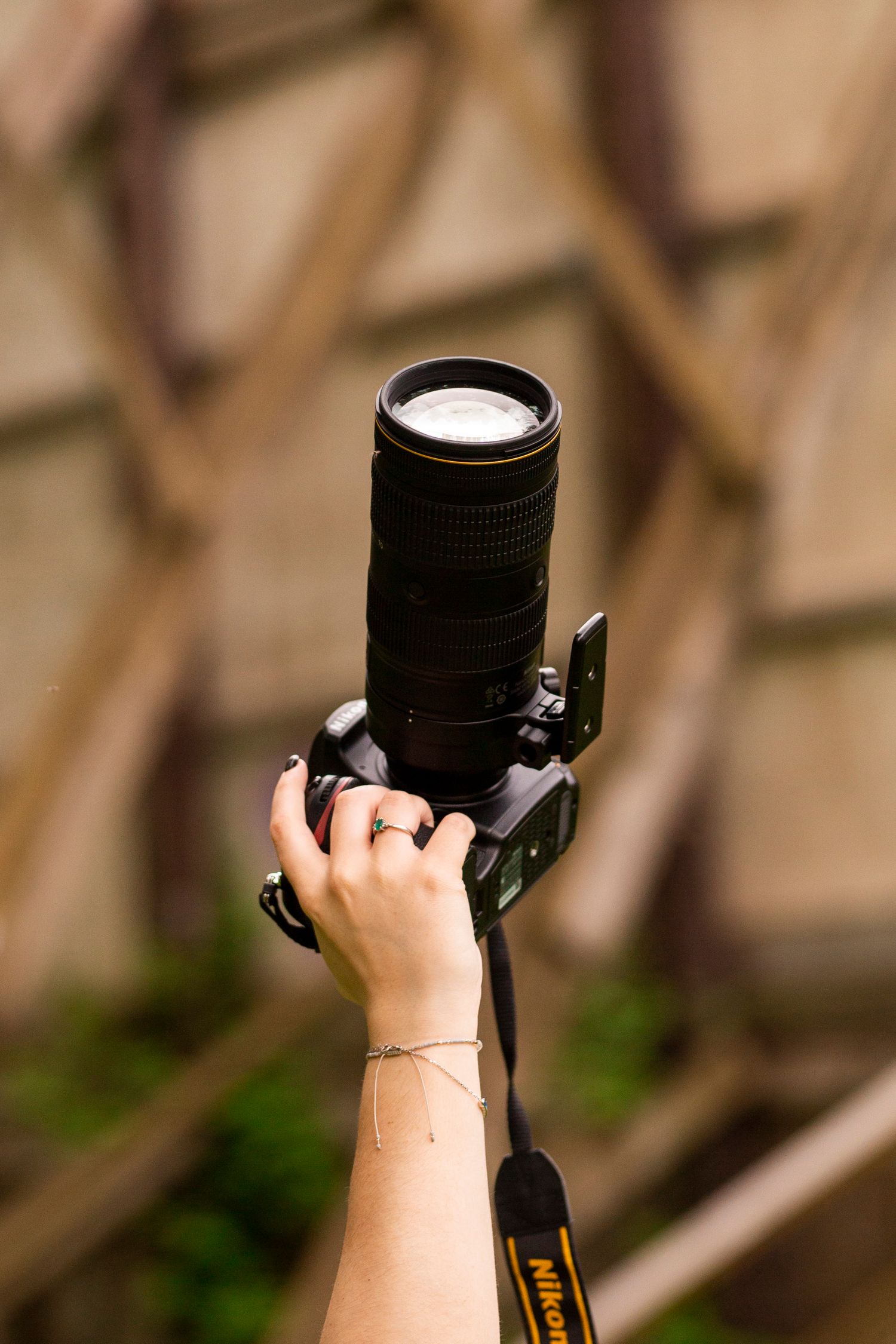 Close-up of hands holding professional camera lens against blurred background.