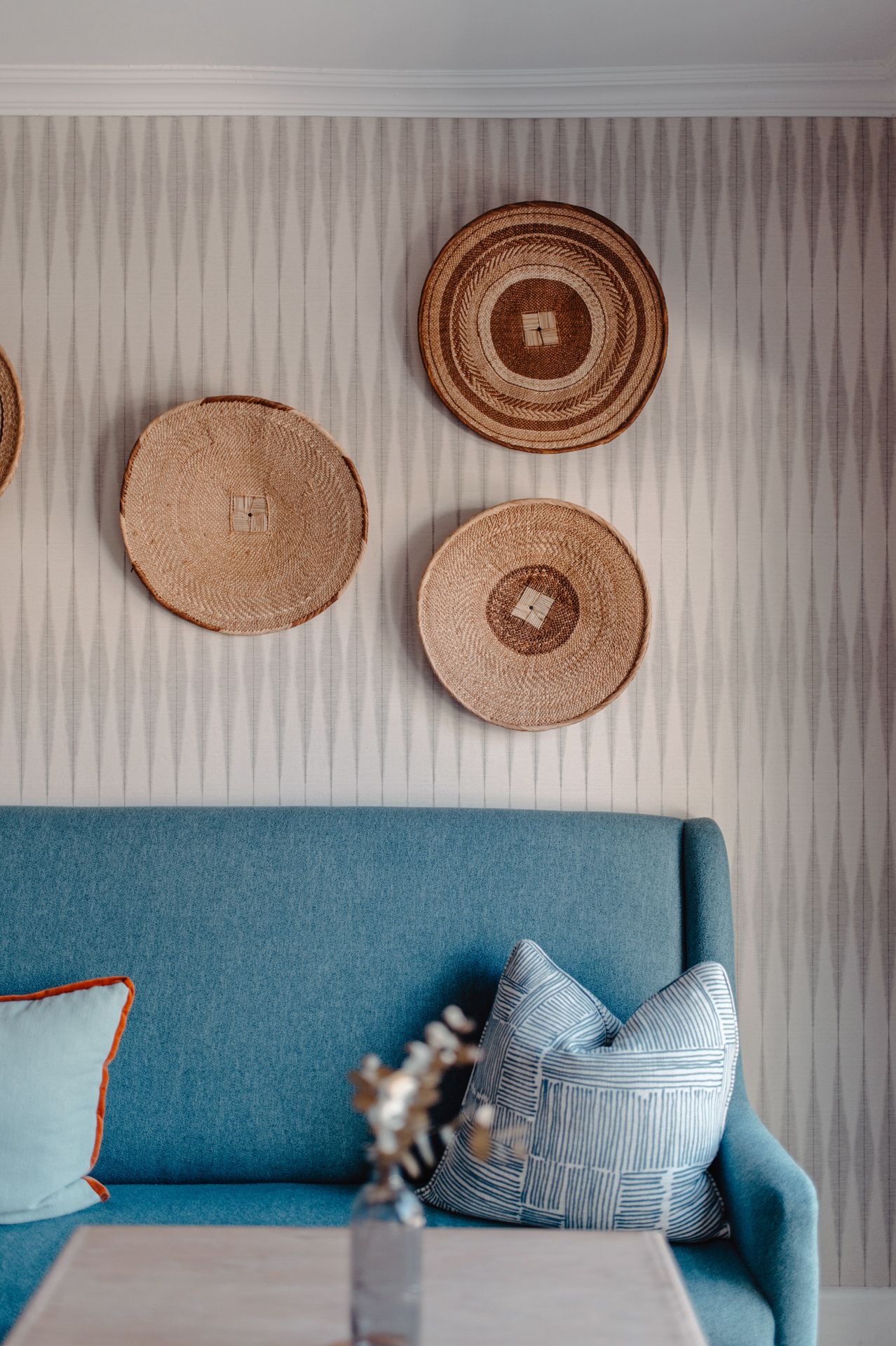 A blue modern sofa with decorative woven baskets mounted on the wall above it.