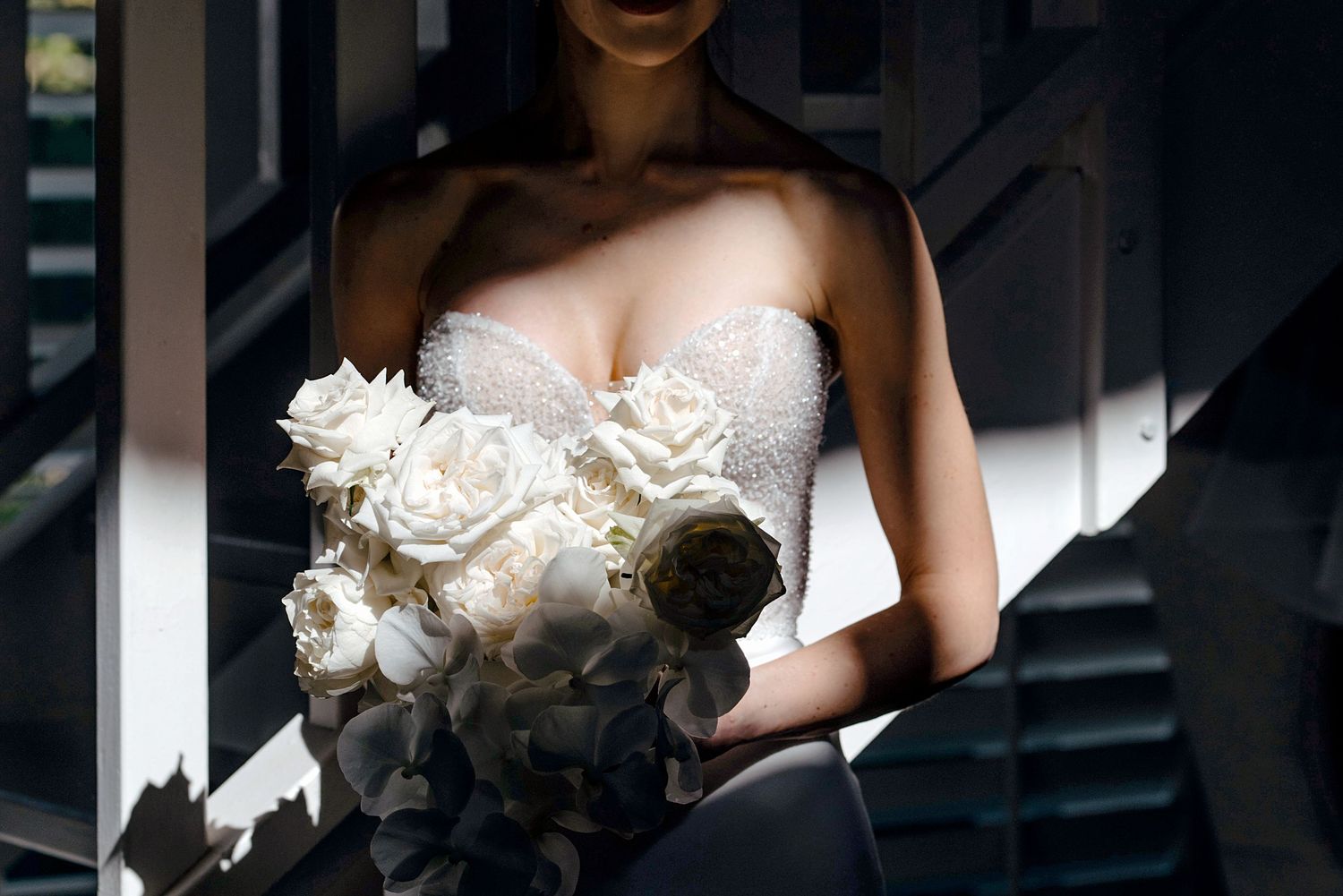 Dramatic silhouette of a bride in a white wedding dress against dark background.