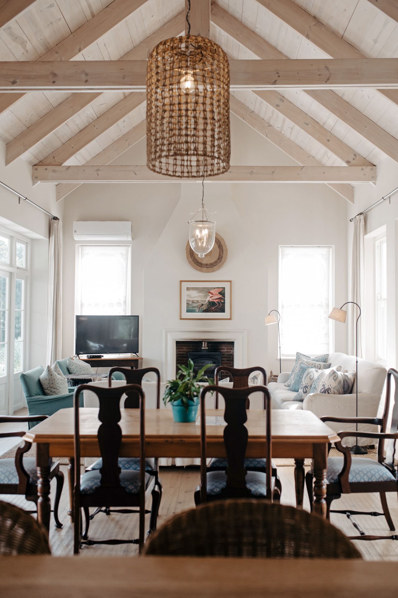 Modern dining room with white vaulted ceiling, woven pendant lights, and dark wood table with black chairs.