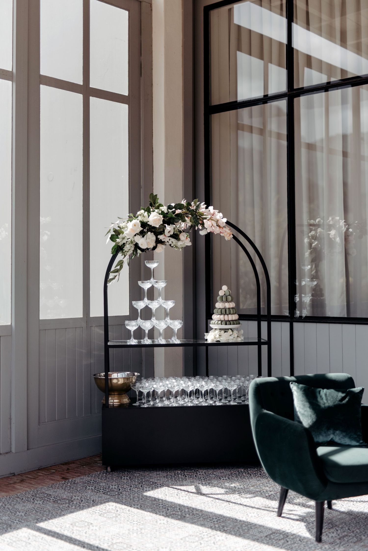 Elegant event space with emerald velvet chairs, floor-to-ceiling windows, and champagne glass displays.