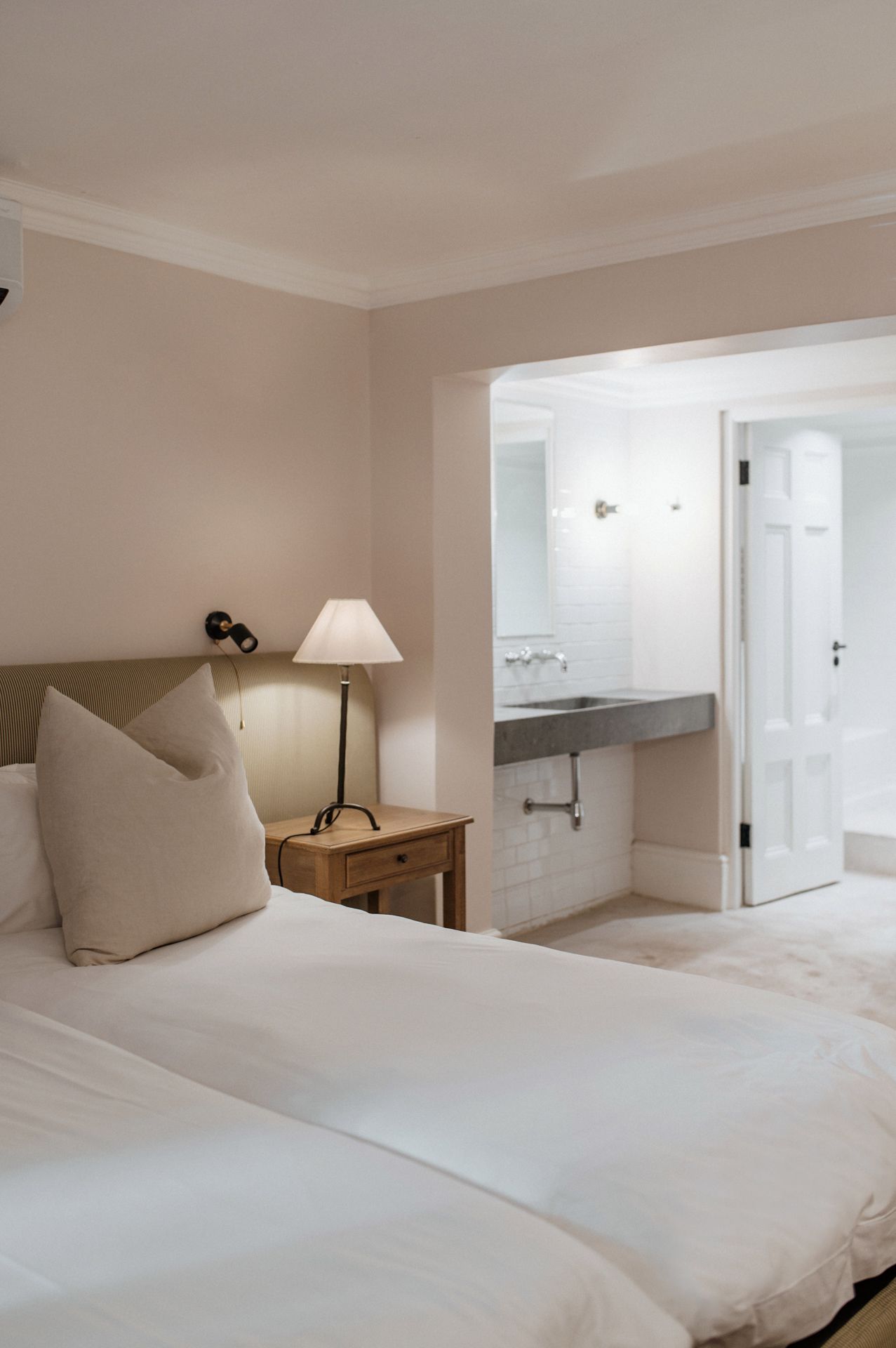 A minimalist white bedroom with built-in storage features and natural lighting showcases clean lines and modern design elements.