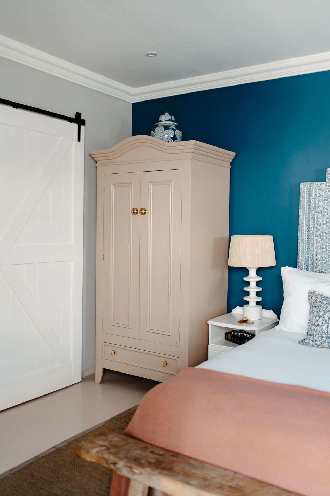 Modern bedroom interior with teal accent wall, white crown molding, and built-in wardrobe storage.