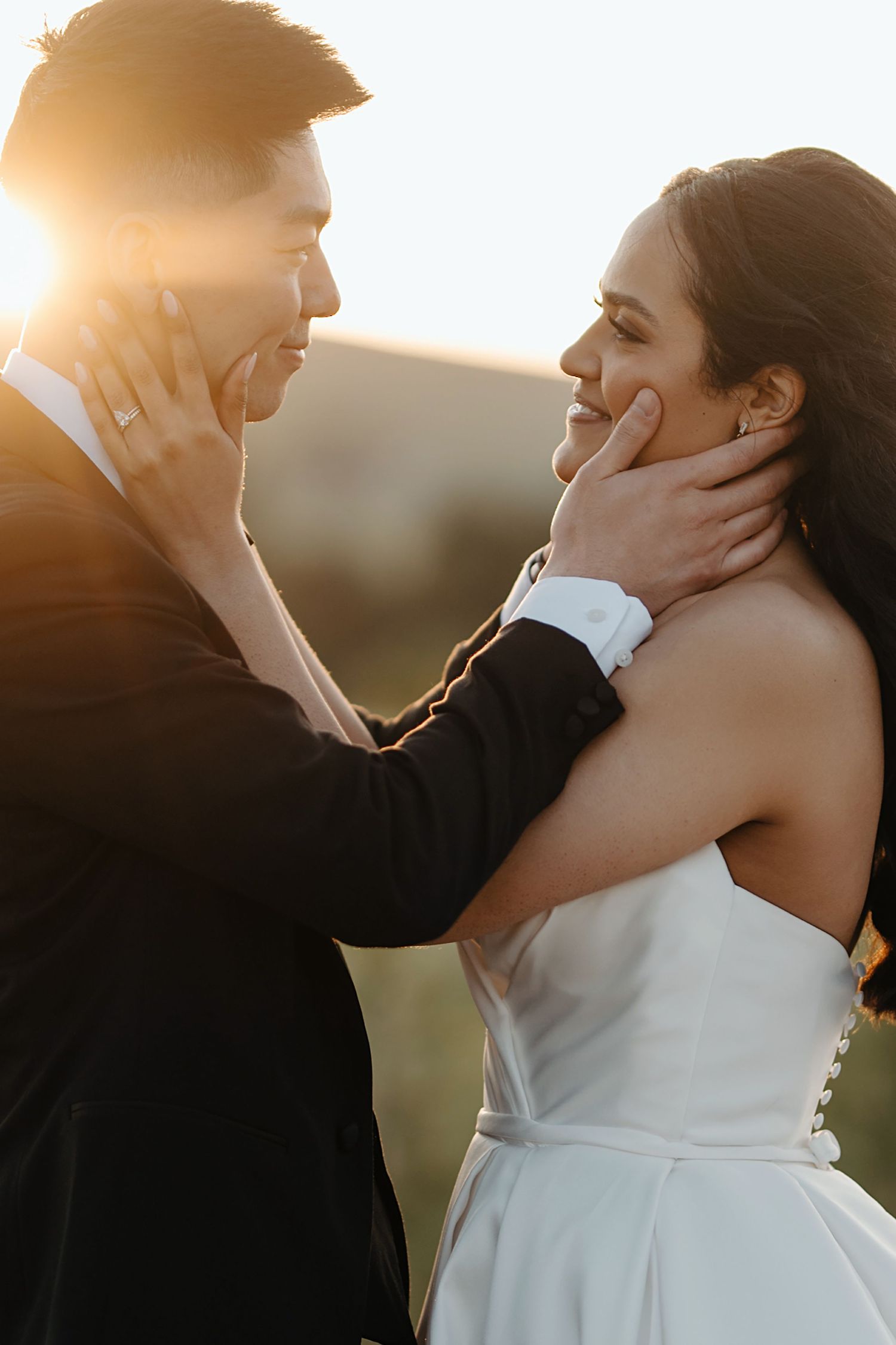 Intimate moment between newlyweds at golden hour with emotional facial expressions.