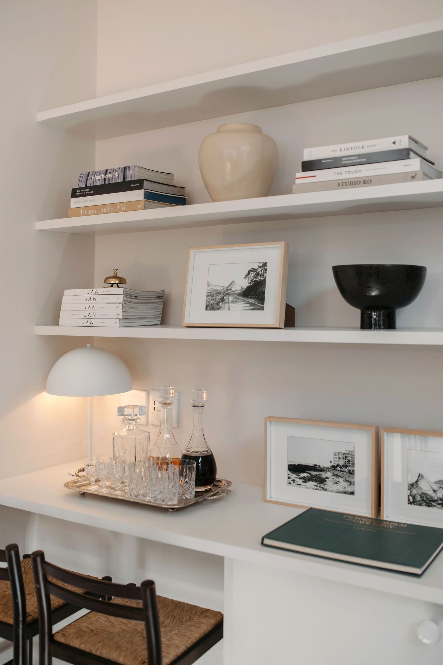White floating shelves displaying books, decorative objects, and artwork create a minimalist wall storage solution.