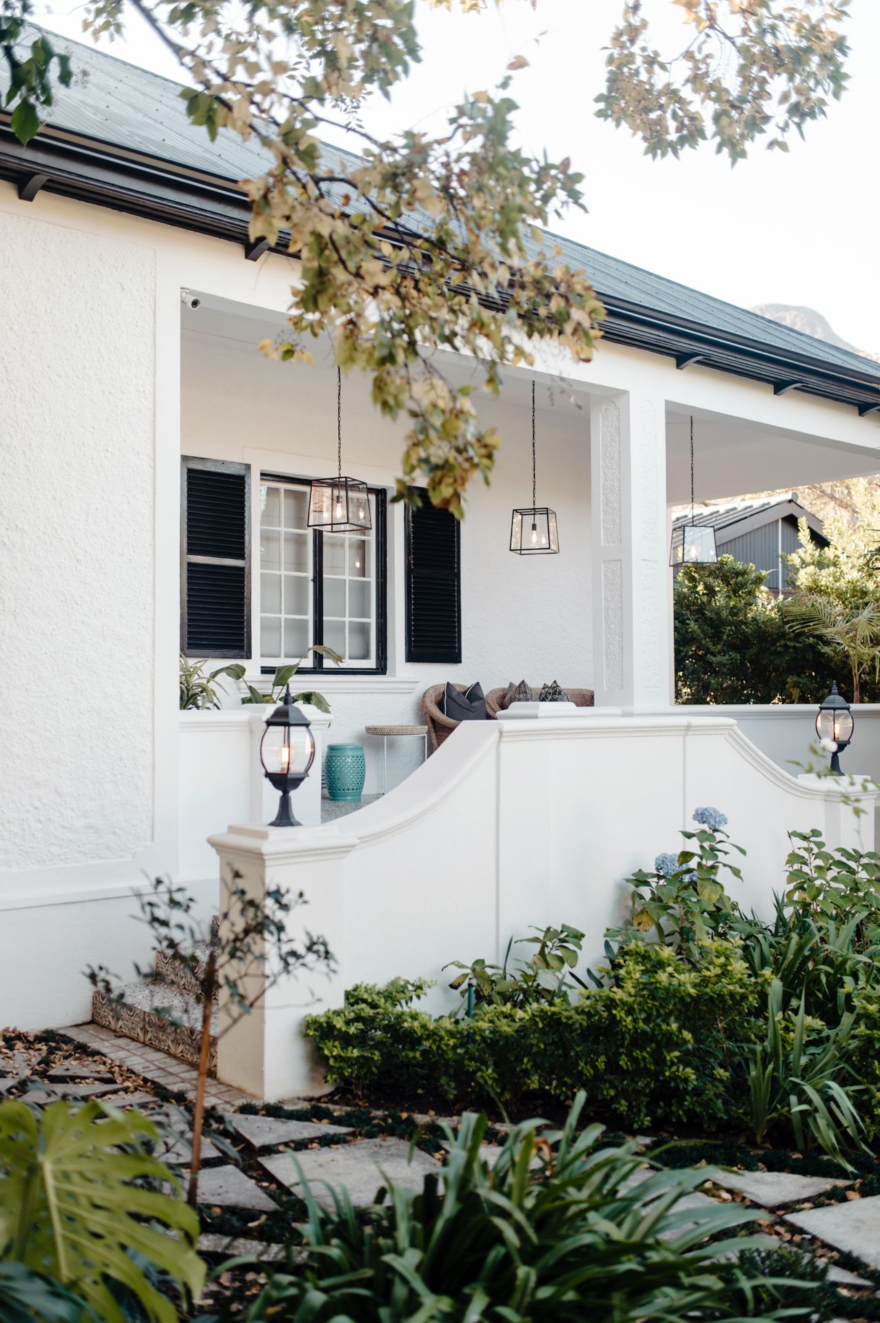 Modern white stucco home exterior with black trim and hanging lantern light fixtures showcases clean architectural lines.