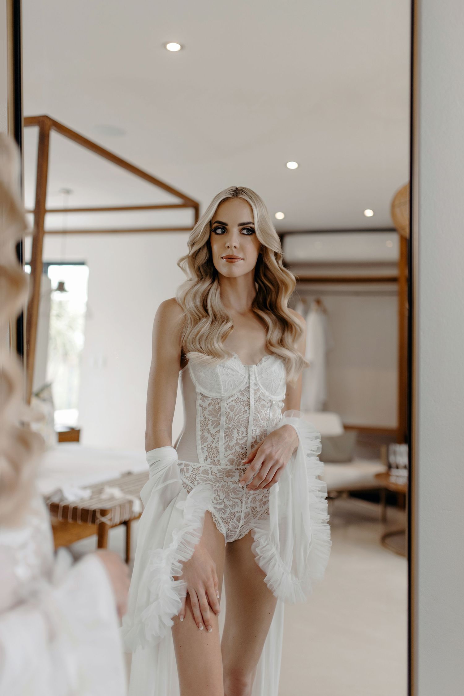 Bridal boudoir photo of woman in white lace lingerie and robe.