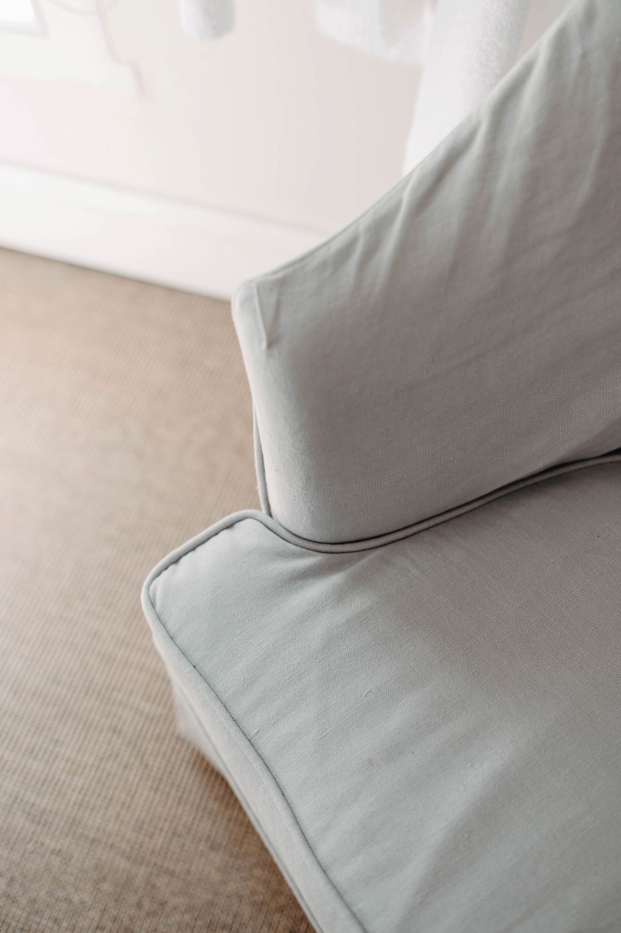 Close-up view of light gray sofa cushion corner showing clean fabric texture and seam detail.