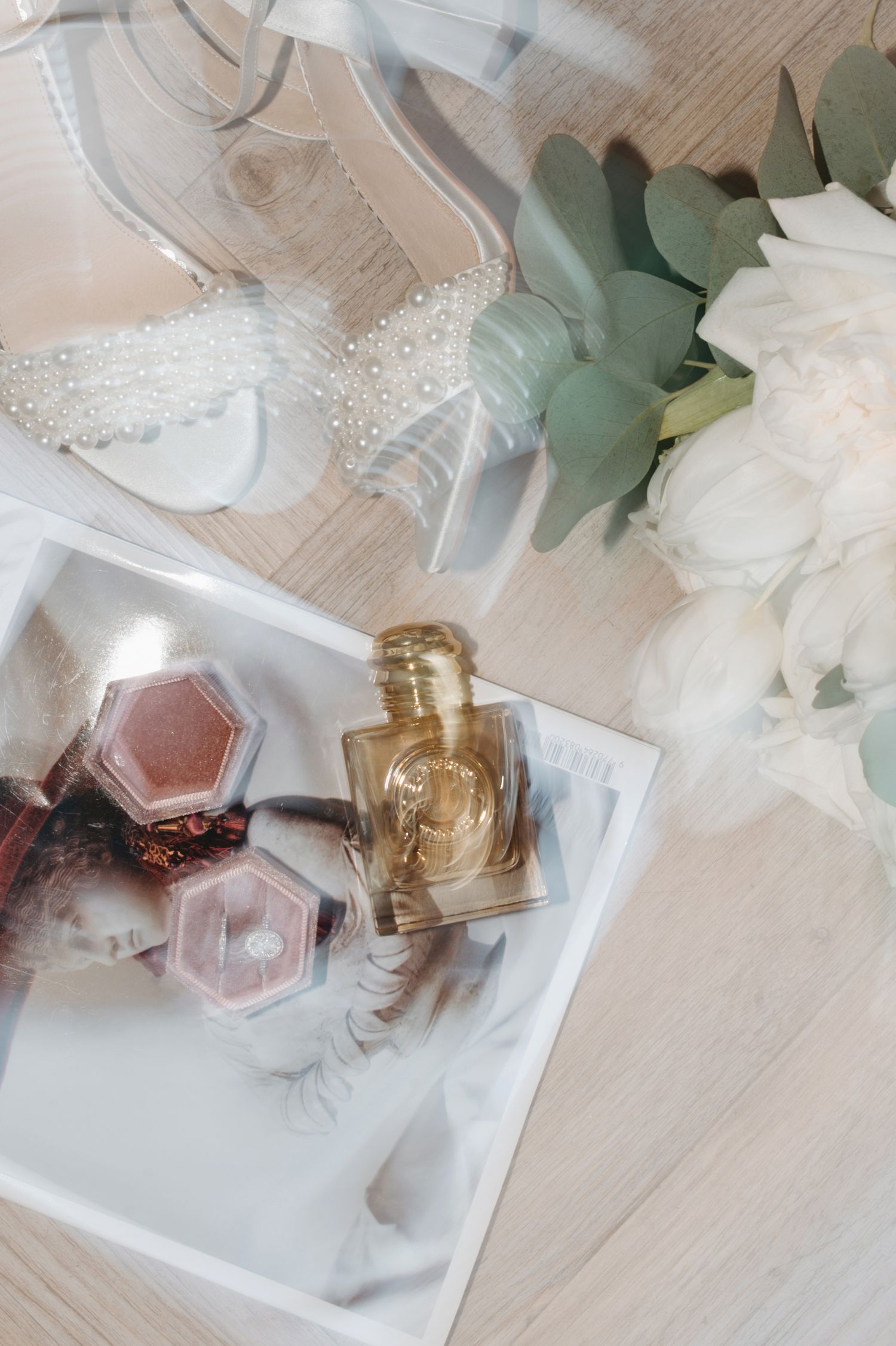 Wedding details flat lay with perfume bottle, eucalyptus and white flowers.