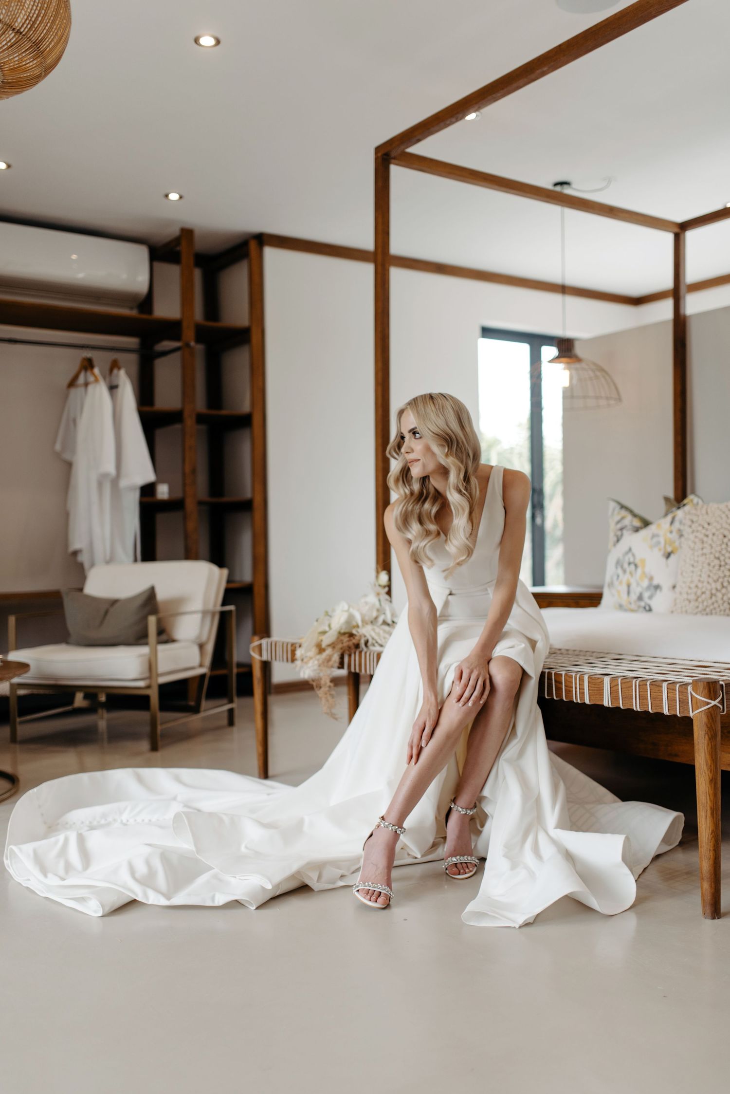Multiple artistic shots of a white wedding dress and heels arranged in an elegant bedroom with wooden accents.