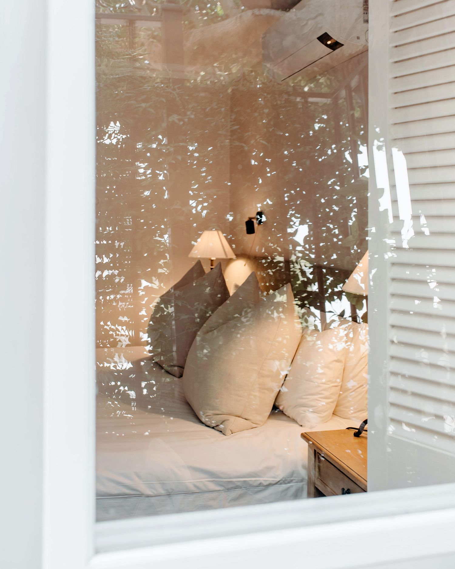 A cozy built-in bed nook with white shutters, soft pillows, and warm lighting creates an inviting sleeping space.