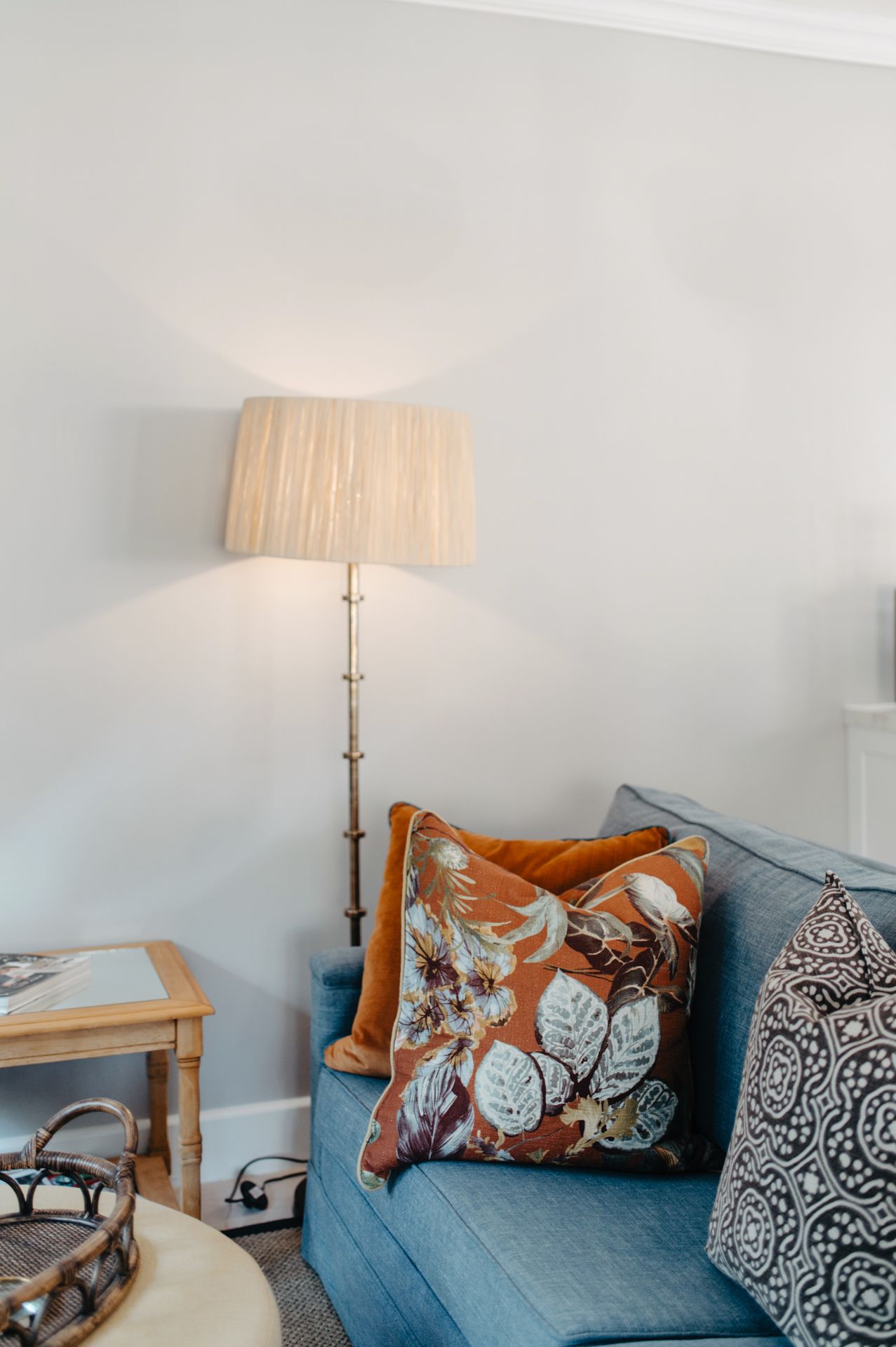 A series of interior photos showing a cozy gray couch with decorative throw pillows and a table lamp with pleated shade.