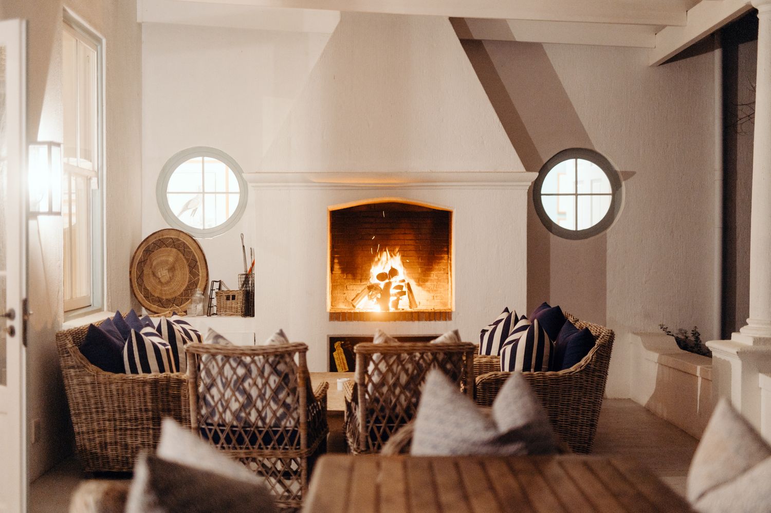 A panoramic view of an elegant living room with white walls, patterned chairs, and circular windows creating a cozy atmosphere.