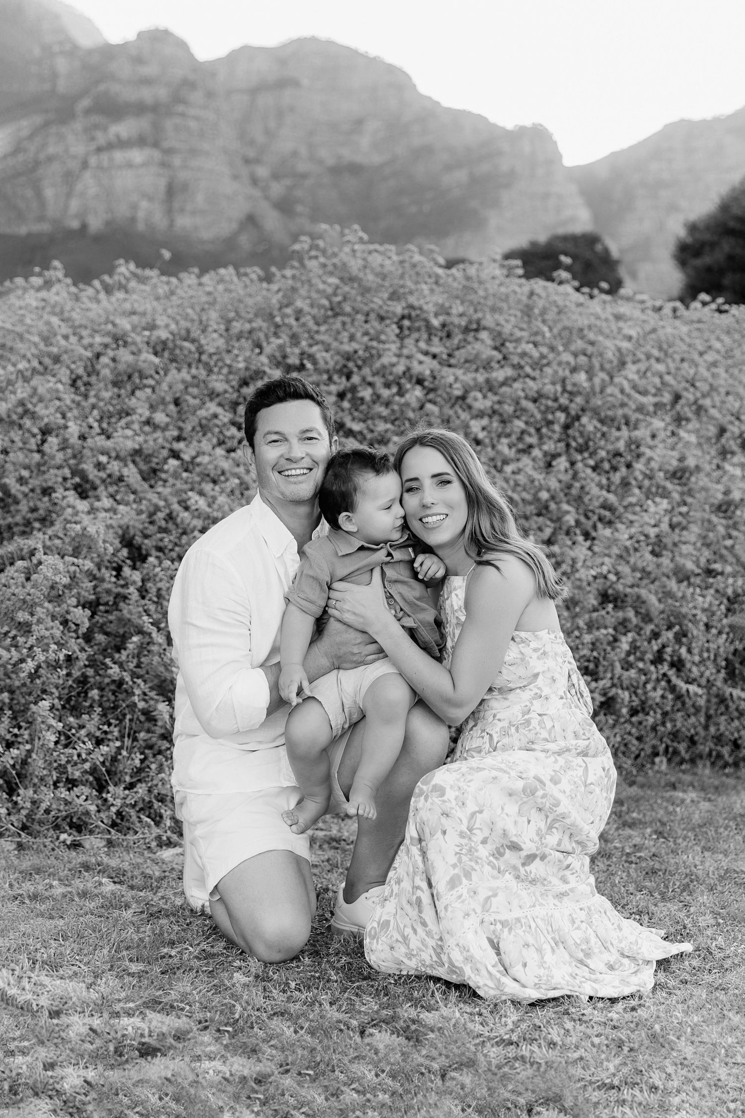 Intimate family moment captured in black and white with mountains in background.