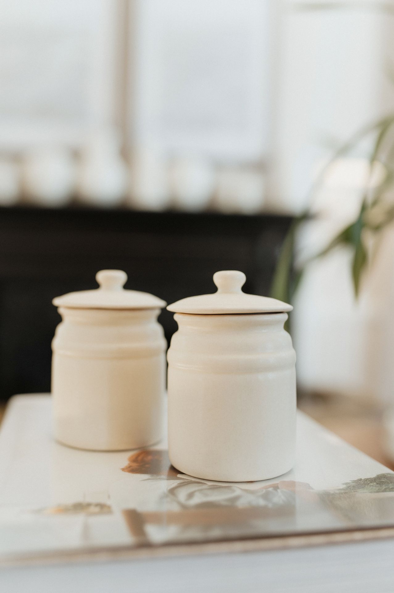 A series of white ceramic pots with lids shown in different angles on a blurred background.