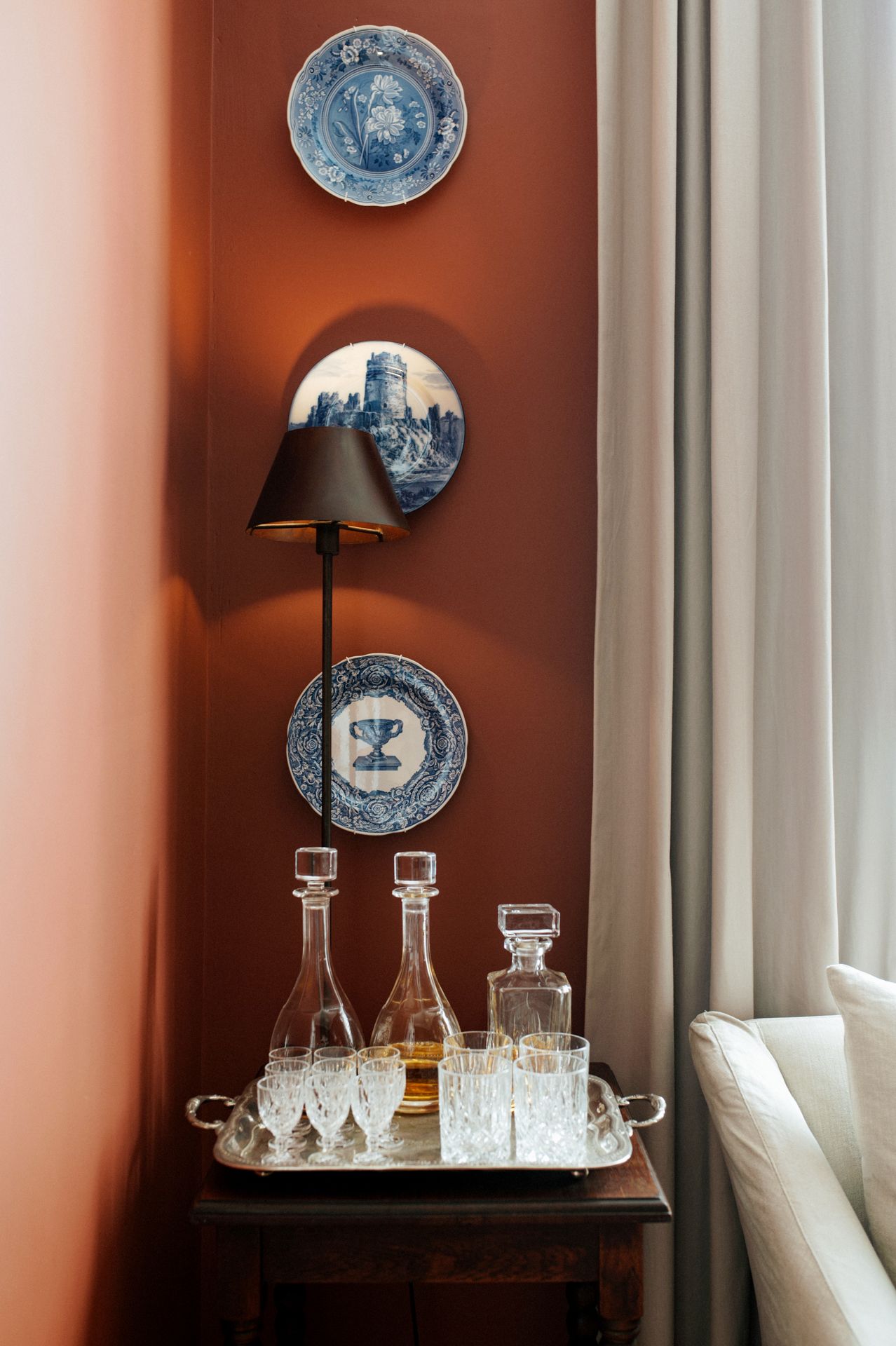 Elegant dining room wall decorated with blue and white decorative plates above crystal decanters and glassware.