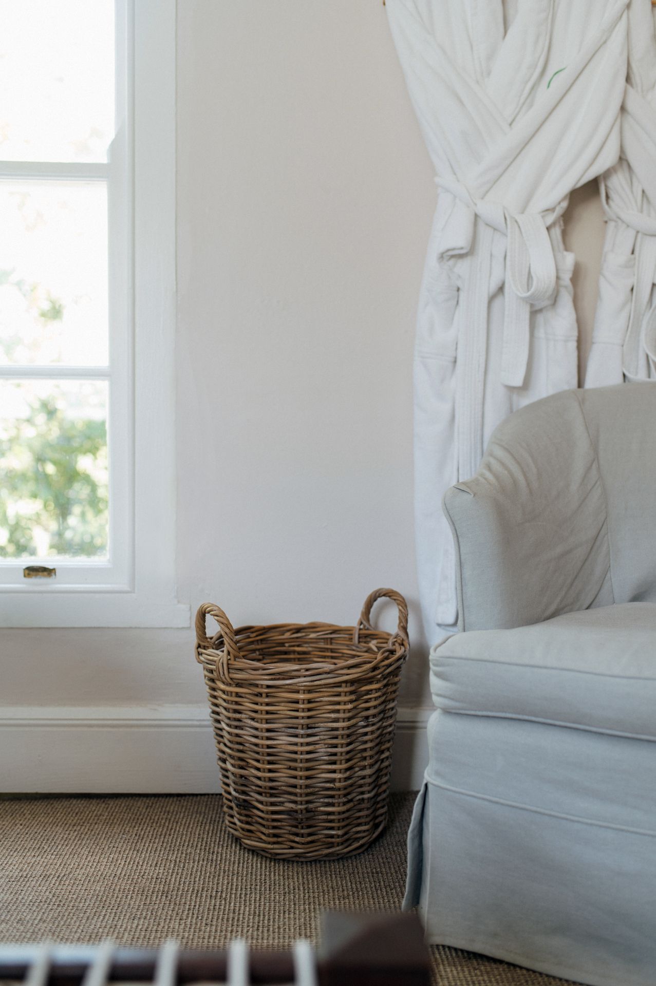 A series of four images showing a wicker basket against white curtains and furniture in a bright, minimalist room.