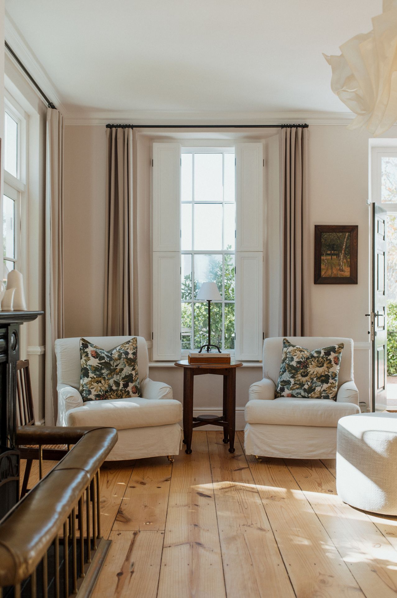 Bright coastal living room with wide plank pine floors, white walls, and comfortable seating near large windows.