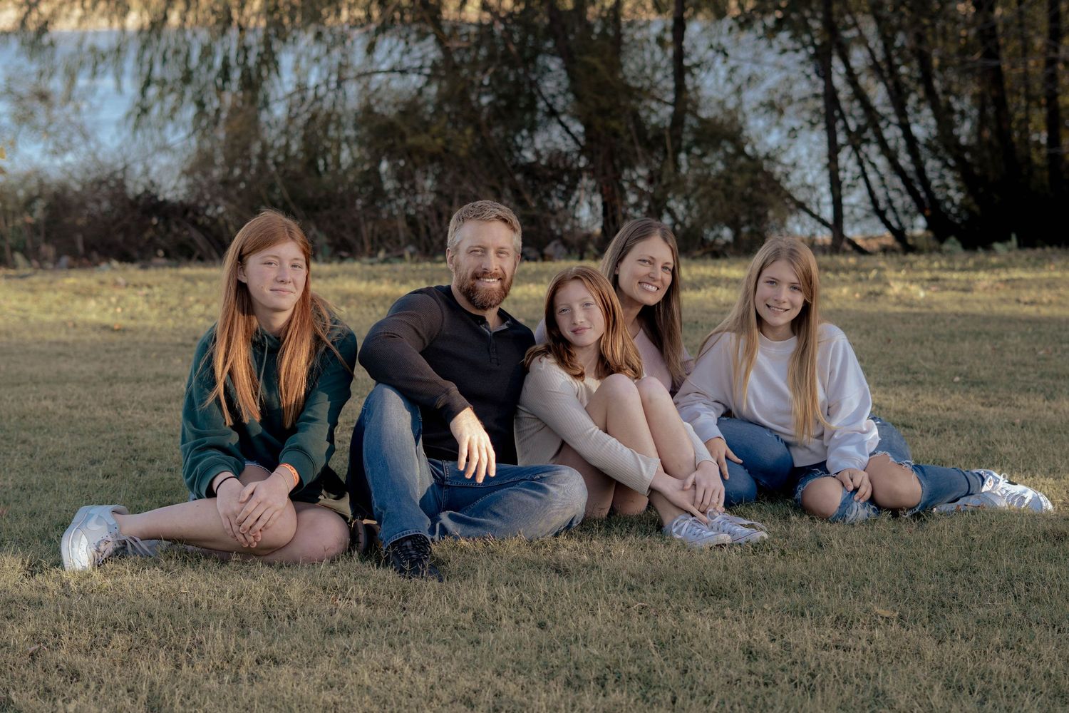 Group of people lying casually on grass in a park during a sunny day outdoors.
