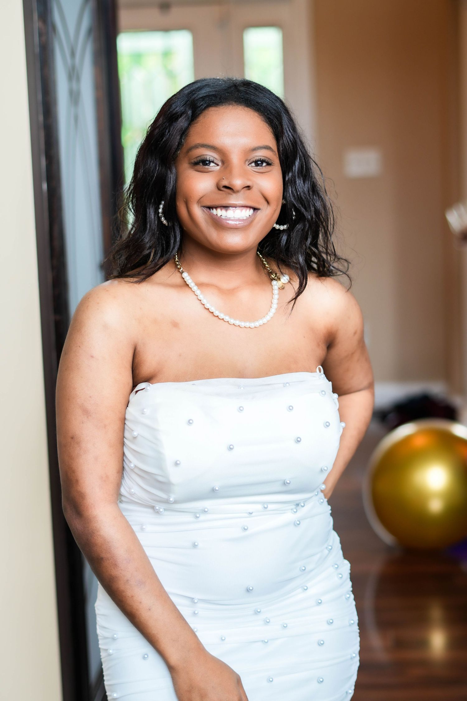 A series of portraits showing a person in a white strapless dress and pearl necklace against a warm interior background.