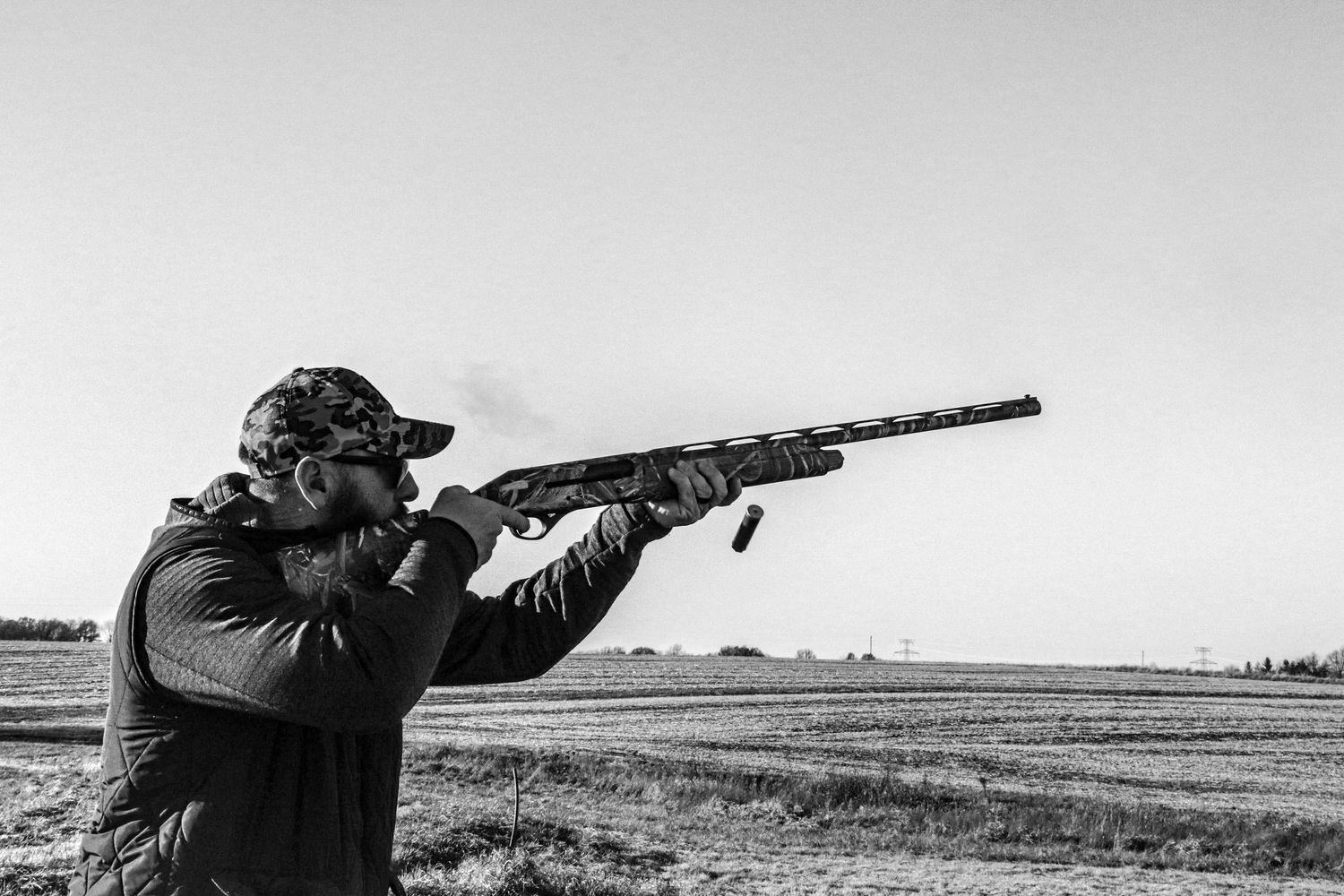 A series of black and white photos showing hunters aiming rifles while standing in open fields.