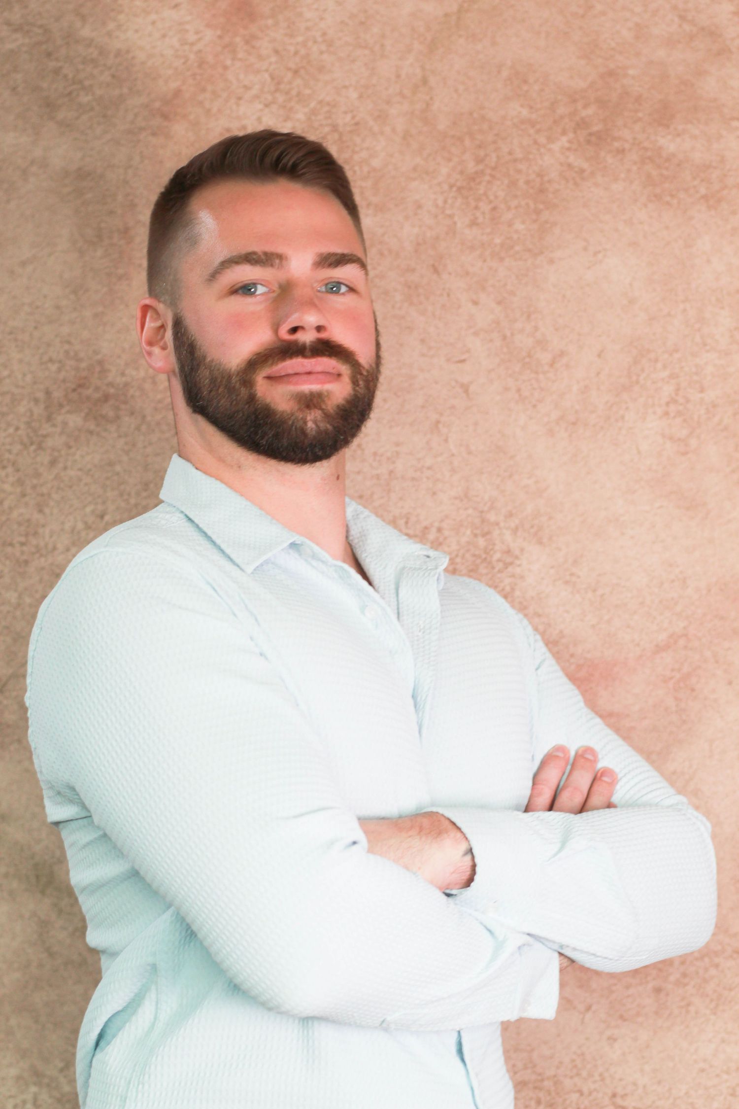 Person in light blue button-down shirt with crossed arms and confident smile.