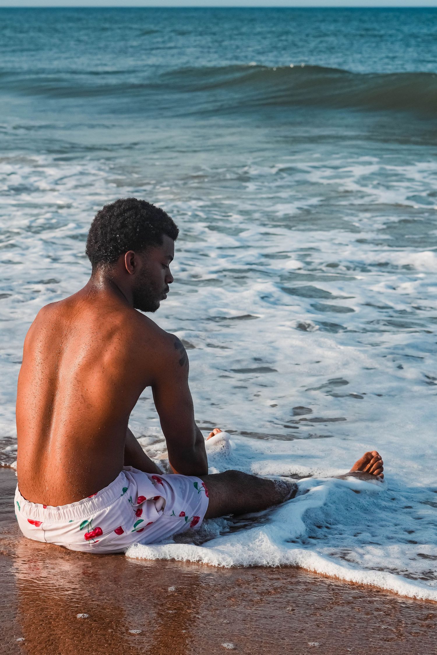 Person relaxing on beach as ocean waves roll in during sunset.