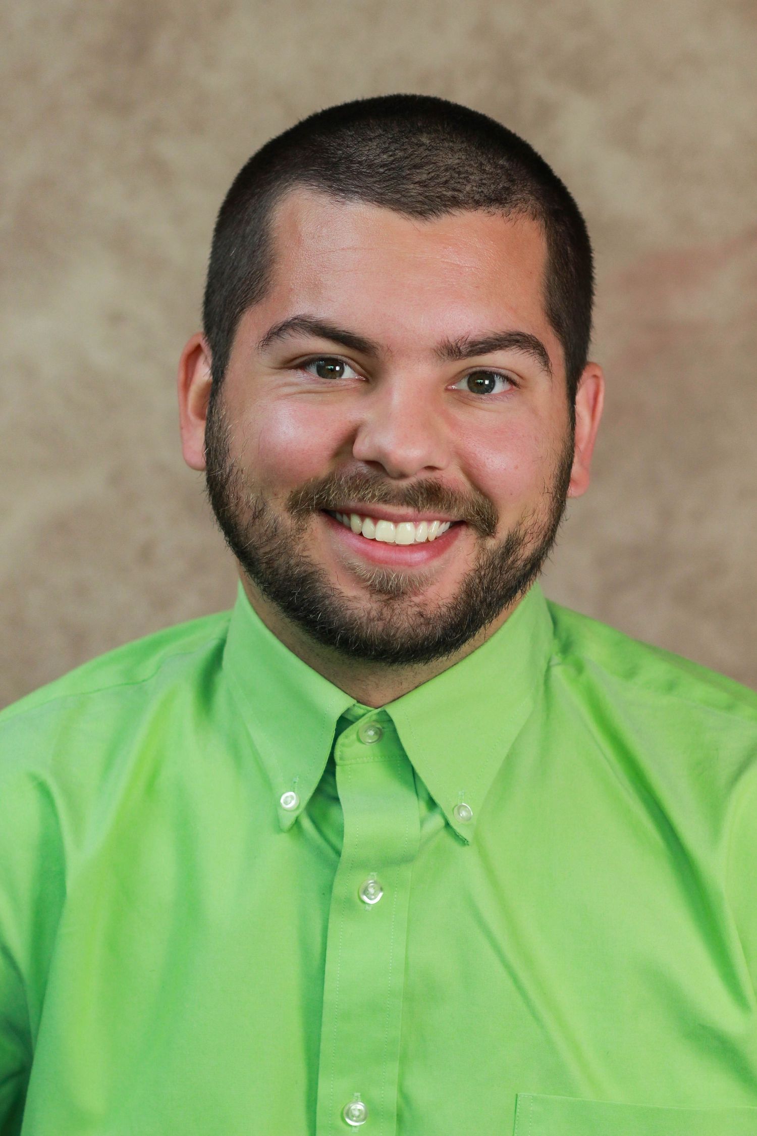 Smiling person wearing bright lime green dress shirt and tie in professional portrait.