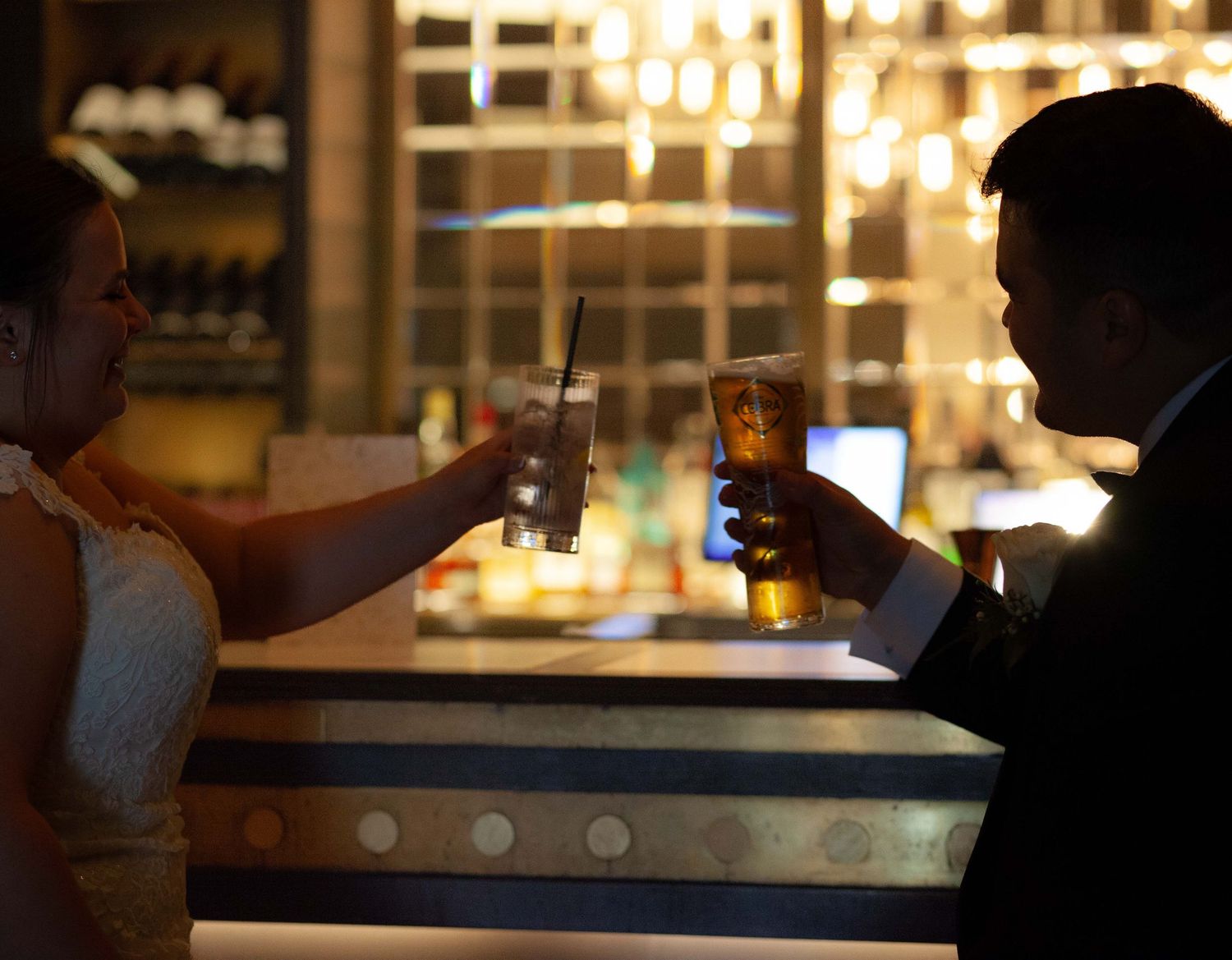 Newlyweds toast each other against the backdrop of a modern bar setting. Micro wedding photographer Ruby Salmon Photography