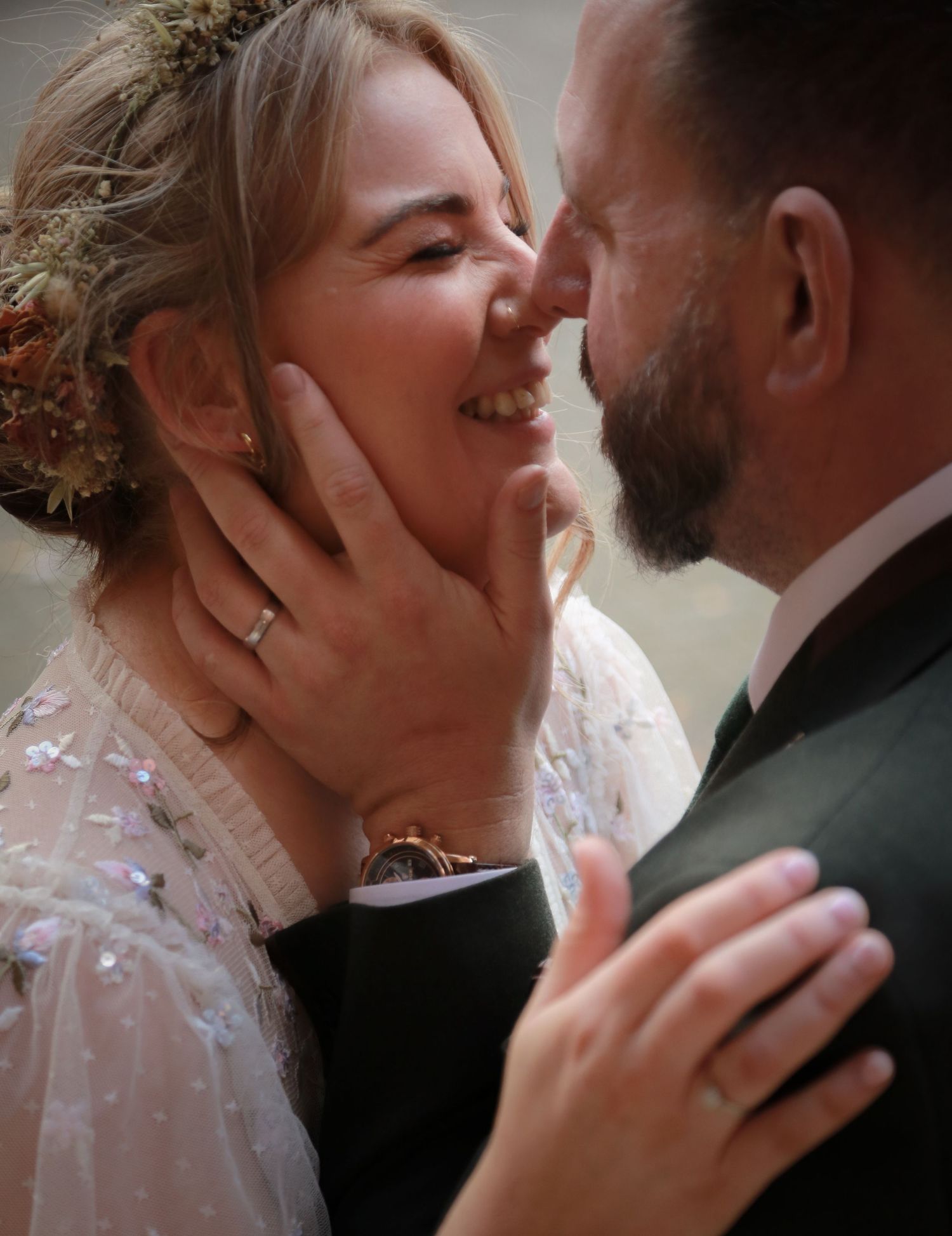 A joyful bride and groom share a tender moment, nearly kissing, as he gently cups her smiling face on their wedding day. Ruby Salmon Photo