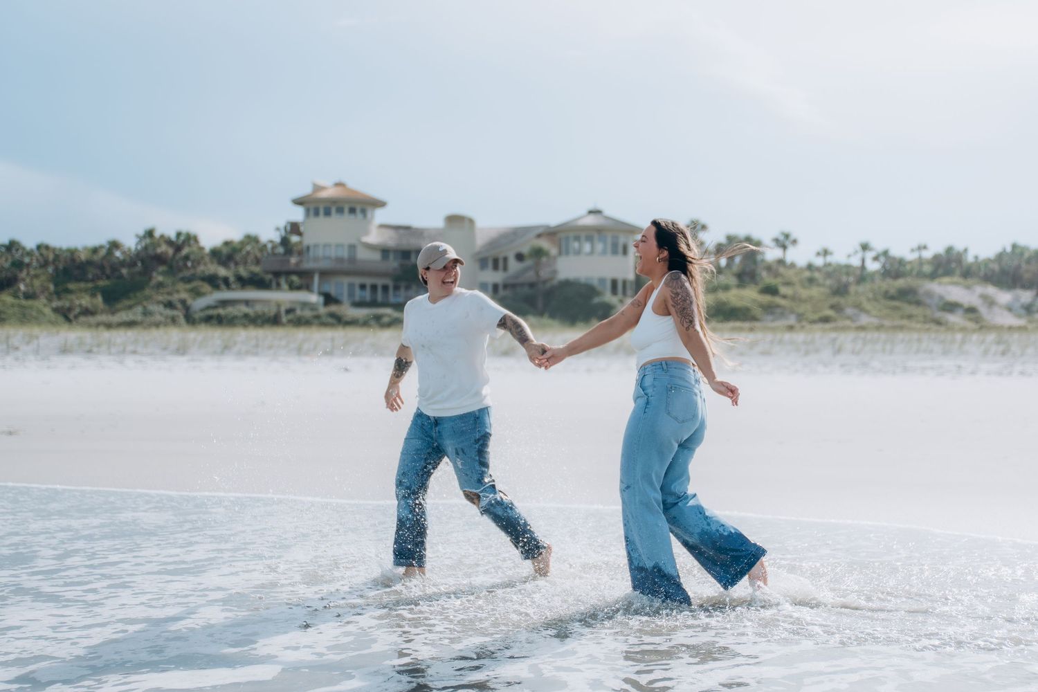 People in matching jeans and white tops playing in the ocean surf.